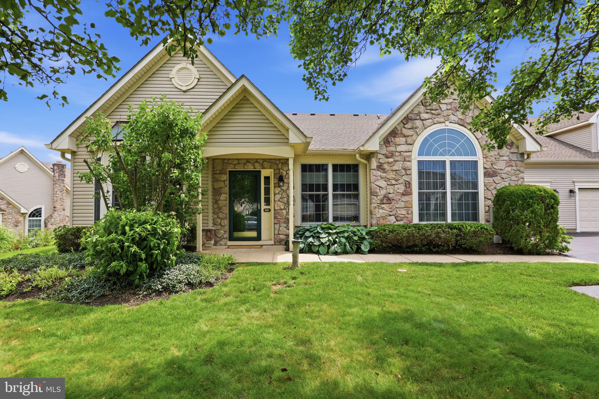 Welcome home to 307 Starflower Lane, a Thornhill Model Quad in the highly desirable 55+ community of Flowers Mill. The Thornhill is one of the community's most popular floor plans, offering a spacious and versatile layout designed for comfortable everyday living and entertaining.  A charming covered entry welcomes you into the spacious living and dining room, where vaulted ceilings create an inviting first impression. To one side of the living room is the primary suite, featuring vaulted ceilings and large windows on two walls that fill the room with natural light. The impressive en-suite includes a walk in closet, an additional double closet, and a beautifully renovated luxury bathroom featuring updated designer lighting, custom decorative mirrors, an oversized double vanity with abundant counter space, and highlighted by a zero clearance entry walk-in shower thoughtfully designed to deliver a luxurious spa like experience while offering exceptional ease of access.  On the opposite side of the home is the second bedroom with new carpeting, conveniently located next to an updated full bathroom.  At the heart of the home is the expansive kitchen and family room, designed for both everyday living and effortless entertaining. The kitchen features new quartz countertops, stainless steel appliances, recessed lighting, and an open layout overlooking the family room. This inviting space is highlighted by a one of a kind gas fireplace, soaring vaulted ceilings, and a dramatic wall of windows that floods the room with natural light, creating a stunning focal point and bringing the outdoors in.  Just off the family room, a covered patio provides the perfect place to enjoy your morning coffee, unwind with a good book, or entertain guests in comfort.  The first floor is completed by a functional laundry room with access to the attached two car garage, which includes an additional storage closet, as well as the staircase leading to the finished second floor loft. Complete with custom built in shelving and an updated full bathroom, this versatile space offers an ideal third bedroom, home office,  or hobby room.  Thoughtfully designed with generous living spaces and flexible rooms, this home offers the comfort and functionality to fit your lifestyle for years to come.  Notable updates include a new roof (2022), HVAC system (2021), Water Heater (2021)and fresh interior paint (2026).  Residents of Flowers Mill enjoy exceptional amenities, including a clubhouse, indoor and outdoor pools, newly added multipurpose courts for tennis and pickleball, scenic walking trails, and a vibrant calendar of social events and activities.