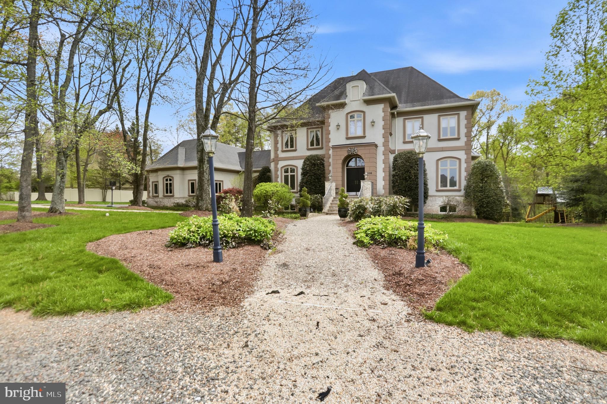 This truly extraordinary French Manor estate is set on two partially wooded acres at the end of a quiet cul-de-sac in the Kentland Farms community of Great Falls. Timeless in its architecture and executed with an uncompromising level of craftsmanship, the residence is defined by its scale, symmetry, and architectural presence—offering a level of finish rarely seen. At its center is a 5-bedroom, 5 full and 2 half bath main residence encompassing over 9,000 square feet across three finished levels, complemented by a beautifully executed carriage house—complete with its own kitchen, living space, bedroom, and bath—connected by a breezeway and designed to function as a fully independent residence.

The main level unfolds with a sense of architectural clarity and proportion, where a dramatic two-story foyer and sweeping staircase introduce a central hall of impressive width and proportion that anchors the home. Ten-foot ceilings, expansive windows, and an abundance of natural light create a sense of volume while maintaining warmth and definition in each space. Formal living and dining rooms are elegantly appointed and distinctly defined, while the kitchen is both substantial and inviting—featuring custom cabinetry, a large center island, and a natural connection to the breakfast room. From here, the home opens to the terrace, where stonework and surrounding landscape create a seamless extension of the interior, accompanied by the soft, natural sound of the creek below. The great room, centered around a floor-to-ceiling stone fireplace, and a private office complete the level with a sense of balance and intention.

Upstairs, introduced by the home’s sweeping staircase, the primary suite is a private retreat of impressive scale, with its own fireplace, dual walk-in closets, and a spa-caliber bath designed with both comfort and proportion in mind. Three additional bedrooms, each with en-suite baths, are thoughtfully arranged, along with an upper-level laundry room positioned for everyday convenience without disrupting the overall flow.

The lower level continues the home’s sense of scale, offering a walk-out recreation room centered around a third fireplace, a private fifth bedroom suite, an additional office, and a dedicated exercise room—creating a fully realized extension of the living space suited for both entertaining and daily use.

The carriage house carries the same architectural language and level of finish, with a fully self-contained residence on the upper level featuring a kitchen, living area, bedroom, and bath, complemented by its own dedicated garage bay. Connected by a breezeway, it maintains a true sense of independence—ideal for multigenerational living, long-term guests, or an au pair residence, with dedicated laundry located at the garage level.

The grounds are as thoughtfully designed as the home itself, set on a serene, wooded homesite with a gently flowing stream and quiet pond creating a private, natural backdrop—offering a setting that feels both secluded and enduring within Great Falls.

Kentland Farms is characterized by its expansive homesites, mature surroundings, and quiet, residential feel, all just minutes from Great Falls Park and the shops and dining of Great Falls Village Centre. The location offers access to highly regarded Fairfax County schools, including the Langley High School pyramid. Commuting is convenient with access to Georgetown Pike, Route 7, and the Dulles Toll Road, with proximity to Tysons, the CIA Headquarters, nearby Silver Line Metro access, and travel to Washington Dulles International Airport and Ronald Reagan Washington National Airport.

A residence defined by architectural integrity, scale, and setting—offered with a level of presence and refinement that is increasingly rare.