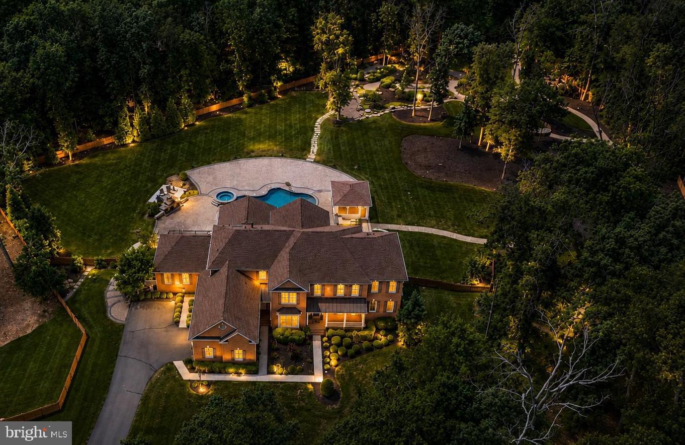 *OPEN SUN 6/28 2-4PM*Priced at Appraised Value*Welcome to the most extraordinary luxury estate in Dominion Valley. Perfectly positioned on the community's largest homesite, a breathtaking 2.21-acre private retreat, this exceptional property offers expansive luxury living, resort-style outdoor amenities and a highly sought-after multigen suite designed for today's lifestyle. Set on a spectacular homesite bordered by community common area on three sides, creating a rare park-like setting, this one-of-a-kind property offers unparalleled privacy, stunning natural surroundings, and the feeling of a private estate while enjoying all the benefits of Dominion Valley's premier gated golf course community.  From the moment you arrive, you'll discover a home designed for both grand entertaining and comfortable everyday living. The gourmet chef's kitchen is the heart of the home, featuring a built-in Monogram refrigerator, double wall ovens, two dishwashers, upgraded cabinetry, granite, oversized island, under-cabinet lighting, and sun-filled solarium addition with skylights and French doors leading to the outdoor living spaces. Elegant formal rooms, a private office with custom built-ins, a conservatory, Palm Beach sunroom, and expansive family room with coffered ceilings and stacked stone fireplace create endless possibilities for gathering, working, and relaxing.  One of the home's most desirable features is the private main-level multigen suite complete with its own living room, spacious bedroom, luxury bath, walk-in closet, and private entrances to both the front of the home and rear deck, making it ideal for extended family, an au pair, or private home office. A second main-level bedroom with en-suite bath provides even more flexibility.  The luxurious primary suite is a true retreat featuring a sitting room with a dramatic two-sided fireplace, dual walk-in closets, and a spa-inspired bath with soaking tub, oversized walk-in shower, skylight, and dual vanities. Upstairs, additional generously sized bedrooms offer en-suite baths and abundant closet space. The finished lower level provides incredible recreation space with 9-foot ceilings, full bath, future wet bar and 2nd bathroom rough-in, extensive storage, and home theater wiring.  Step outside and experience what truly sets this property apart. The backyard is a private resort unlike anything else available in Dominion Valley. Enjoy the spectacular heated saltwater gunite pool with, fountains, diving board, sun shelf, built-in basketball hoop, and an oversized spa with waterfall. Entertain year-round from the covered pavilion with Phantom screens, heaters, and ceiling fans. Additional outdoor features include an outdoor kitchen with built-in gas grill and beverage refrigerator, covered Trex deck with heaters, fans and gas line for a future built-in gas firepit, wood-burning stone fireplace, gas firepit, pebble lined walking trails, horseshoe pits, Gaga ball pit, basketball hoop, recirculation stream, extensive low-voltage lighting, and an incredible outdoor sound system with approximately 70 backyard speakers. Every detail was thoughtfully designed to create an unforgettable outdoor living experience.  Additional highlights include engineered hardwood flooring throughout the main and upper levels, four-zone HVAC, tankless water heater, Control4 smart home automation, zoned irrigation system, invisible fence, extensive hardscape and landscaping, upgraded sump pump with battery backup, and numerous recent system updates. Living in Dominion Valley means enjoying a true resort lifestyle with a championship Arnold Palmer Signature golf course, renovated clubhouse and fitness center, indoor and outdoor pools, tennis and pickleball courts, sports pavilion, trails, fishing ponds, playgrounds, dining, and social events. Conveniently located near I-66, Routes 29, 50, 15, with easy access to shopping, dining, wineries, breweries, and commuter routes.