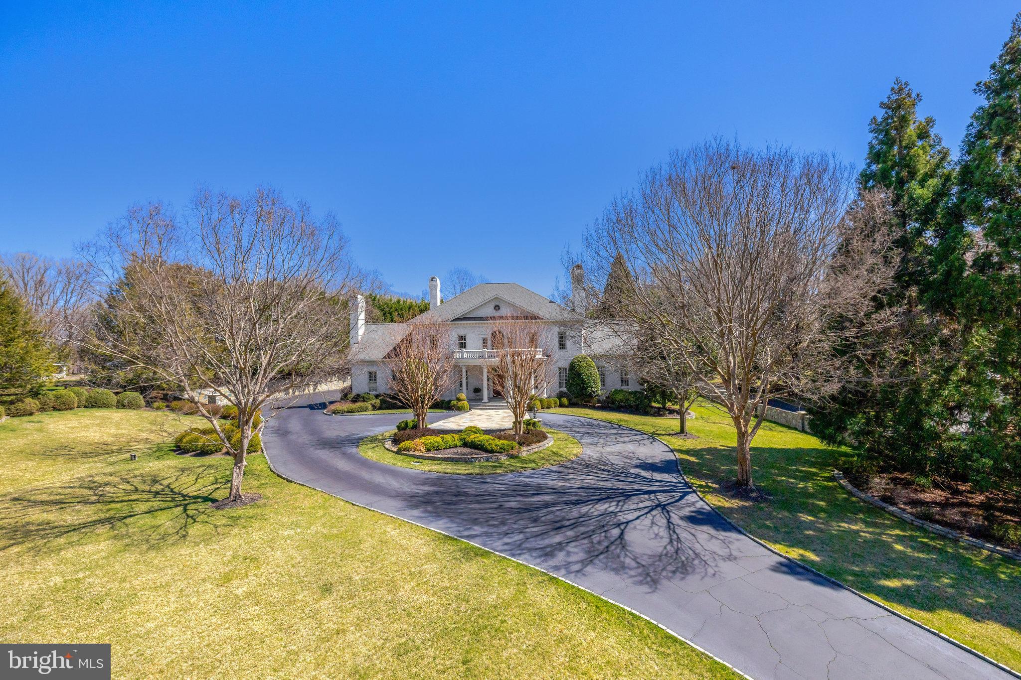 Sitting on nearly 2 acres, this stunning estate offers 5 spacious bedrooms, 6 bathrooms, and over 8,429 SQFT of refined living space, including a primary bedroom on the main level for added convenience. The interior is complemented by picturesque views of meticulously manicured gardens. The grand foyer, featuring marble flooring, sets the tone for the home’s sophisticated design. The formal living room boasts a striking wood-burning fireplace, while the gourmet kitchen, equipped with Viking appliances and custom cabinetry, provides the ideal space for both cooking and entertainment.  The primary suite, located in its own private wing, is a luxurious retreat with an expansive walk-in closet and unparalleled comfort. Upstairs, each en-suite bedroom is spacious and thoughtfully designed, with bedroom 5 offering private staircase to the mudroom. The lower level is perfect for entertaining, featuring a full wet bar, game room, and a clubroom with a striking stone wall and wood-burning fireplace. A dedicated exercise room and additional flexible living spaces, including a bonus room with a full bath, provide versatile options to suit any lifestyle. This home combines elegance, functionality, and a breathtaking setting.
