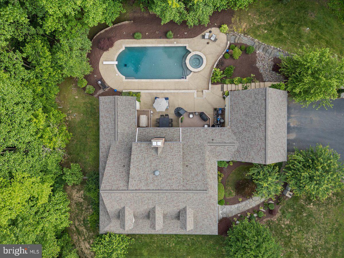 Tucked away in a setting of complete privacy, this captivating residence is a rare offering where charm, craftsmanship, and thoughtful upgrades come together effortlessly. Meticulously maintained and curated with intention, every space tells a story—one of quality, comfort, and timeless design. From the moment you enter, the home reveals its character through exquisite details: custom built-ins, carved wood ceilings, and beautifully refinished hardwood flooring that flows throughout. The heart of the home is both inviting and refined, anchored by a striking Wolf stove and complemented by a cozy fireplace and soaring vaulted ceilings. Designed for both everyday living and exceptional entertaining, the main level features two full baths, including a serene primary suite that offers a true retreat. Upstairs, you’ll find a private bedroom with its own en-suite bath, along with two additional bedrooms—one thoughtfully designed with a hand-painted forest mural, creating a whimsical and memorable space. Adding to the property’s versatility is a finished garage with a dedicated studio/workspace and a complete guest suite above, offering a full bath, bedroom, and separate work area—ideal for extended stays, creative pursuits, or private accommodations. The lower level has been recently finished, providing additional living space with a bedroom, expansive recreation or fitness area, and a convenient half bath with direct access to the outdoor amenities. Step outside and experience a true resort-like setting. The saltwater pool, just four years old, features a PebbleTec finish and a built-in spa, surrounded by extensive landscape lighting and color-changing pool illumination—creating an atmosphere that transitions seamlessly from day to evening. Ample parking and a large storage building ensure both function and convenience. Located less than an hour from Washington, D.C. and Annapolis, Maryland, this property offers the perfect balance of seclusion and accessibility. A private retreat of uncommon quality—designed to restore, inspire, and elevate everyday living.