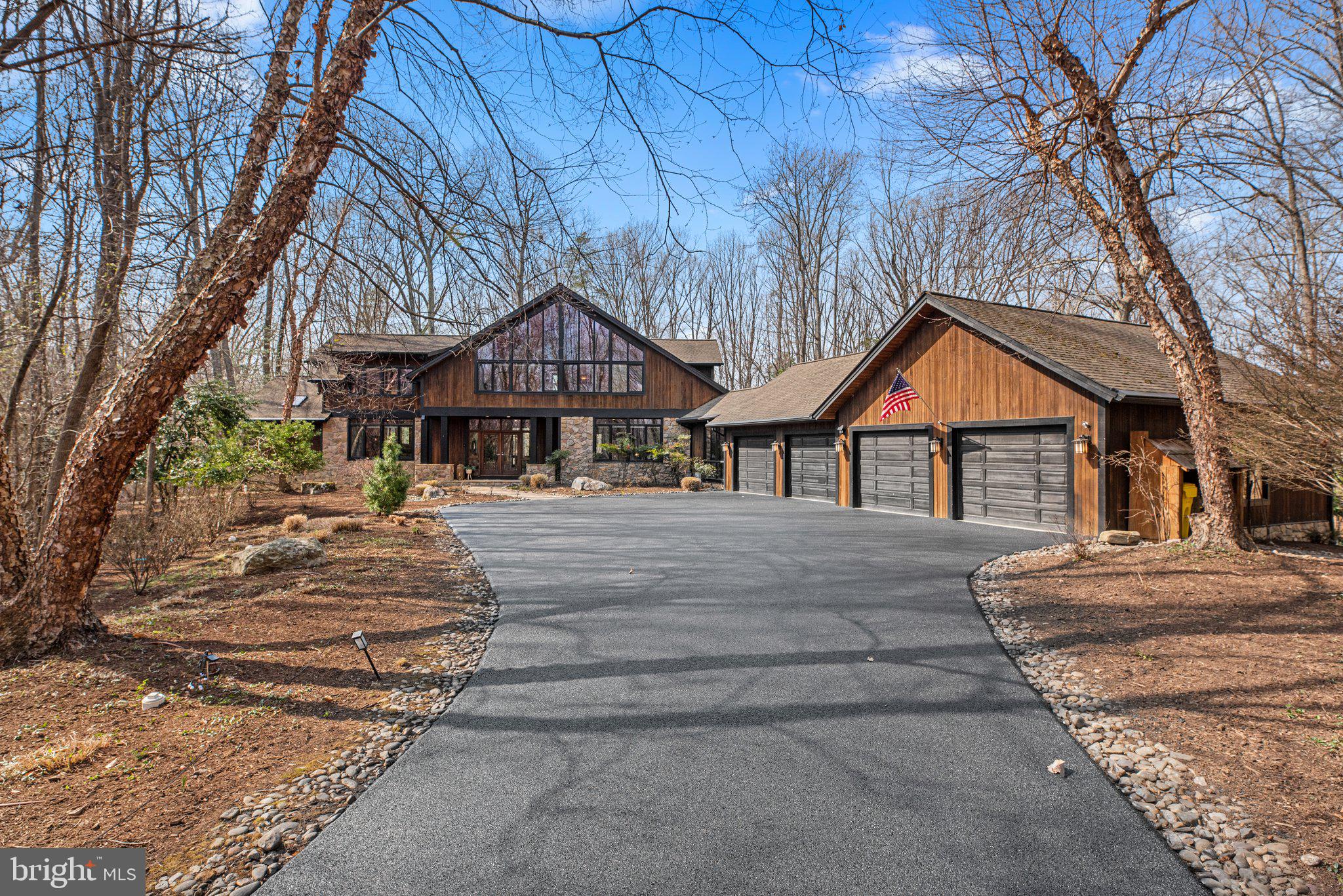 Mid-Century Modern Elegance exudes in this Custom Acorn Deck House Near Annapolis in Sought-After Belvoir Farms. Tucked away on a 1.23-acre wooded lot, this one-of-a-kind 6,500+ SF, 6-bedroom, 5.5-bath, 4-car garage Acorn Deck House is a stunning example of mid-century modern architecture seamlessly integrated with nature. With its signature post-and-beam construction, mahogany millwork, and soaring floor-to-ceiling windows, this architectural gem offers timeless craftsmanship and an inviting retreat from the everyday. A custom-designed fountain greets you and your guests upon arrival, setting the tone for the serene experience that awaits. A scenic driveway leads to this private sanctuary, where thoughtful hardscaping, Zen-inspired gardens, a stocked koi pond, and a kidney-shaped spa create a tranquil outdoor oasis. Expansive patios, a screened-in porch, and lush landscaping featuring rare species like Dancing Peacock Japanese Maples and Snowboy Dogwoods enhance the natural beauty of the setting. With no visible neighboring homes from the backyard, this property offers an exceptional sense of seclusion and privacy. Inside, the rich Brazilian cherry hardwood flooring and cabinetry, tongue-and-groove ceilings, and walls of windows showcase the home’s signature design. A custom-designed library with wall-to-wall cherry shelves and cabinets provides a sophisticated space for reading or work. The gourmet mahogany and granite kitchen is a chef’s dream, featuring high-end appliances (Thermador, KitchenAid), including two built-in ovens, a microwave, a proofing oven, a trash compactor, a reverse osmosis system, and a walk-in butler’s pantry equipped with a mini-fridge for cooling your favorite beverages. The main-level Primary Suite offers a gas stone fireplace, cedar walk-in closet, and spa-like bath, creating a private retreat. An oversized mudroom with dual sink/work areas provides functional elegance and ample storage. The upper level includes a loft-style office, four spacious bedrooms (one ensuite), and two additional full baths, while the lower level features a cozy fireside lounge, theatre space, gaming area, workout room, full bedroom, and full bath. A newer basement kitchen adds convenience, with direct access to the outdoor spa and patios; perfect for entertaining or multi-generational living. The lower level is also plumbed for an additional washer and dryer, providing further flexibility. Additional features include: All-house audio speaker system for seamless entertainment, custom high-speed WiFi installation, expansive windows framing ever-changing foliage, sunrises, and sunsets, extensive drip irrigation system for effortless landscaping maintenance, three custom-designed workbenches in the spacious 4-car garage, whole-house generator for peace of mind, extensive storage space with custom shelving on the lower floor, recently stained and painted exterior for a fresh, well-maintained look. Recent Improvements: Newly updated high-efficiency HVAC systems, water softener & pool heater, Refinished Brazilian cherry hardwood floors and recently repaved driveway. Newer basement kitchen for added functionality and entertaining. Located in the sought-after Belvoir Farms Community, residents enjoy exclusive access to a marina, tennis and pickleball courts, a playground, and year-round social events. Just minutes from Annapolis Mall, with easy commuting routes to Washington, D.C., Baltimore, and BWI Airport, this custom-designed Deck House is a rare opportunity to own a true mid-century modern masterpiece in a serene yet convenient location. Experience the perfect blend of architectural excellence and natural harmony. Schedule your private tour today!