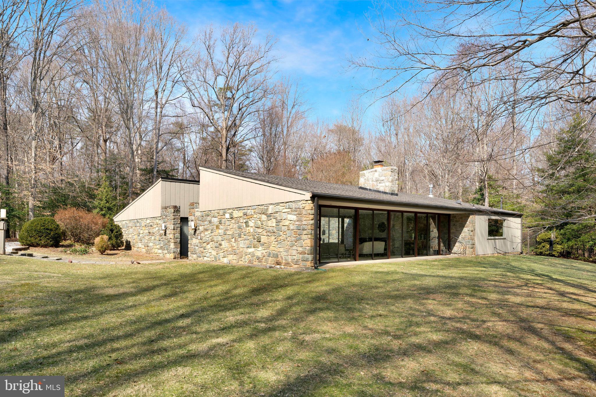 Nestled on 1.8 acres in the heart of Great Falls, this mid-century modern home offers a private retreat with main level living and exceptional design.  Flagstone flooring flows throughout most of the home, creating a seamless connection between the indoor and outdoor spaces.  With windows on all sides, the home is flooded with natural light and offers stunning views into the beautifully landscaped courtyard.  The kitchen is a standout, featuring a large picture window that brings the outdoors in and creates a bright, inviting atmosphere.  With 4 spacious bedrooms and 3 ½ baths, the home is thoughtfully designed for comfort and functionality.  The outdoor space is equally impressive, with a sparking pool and ample space for relaxation and entertainment.