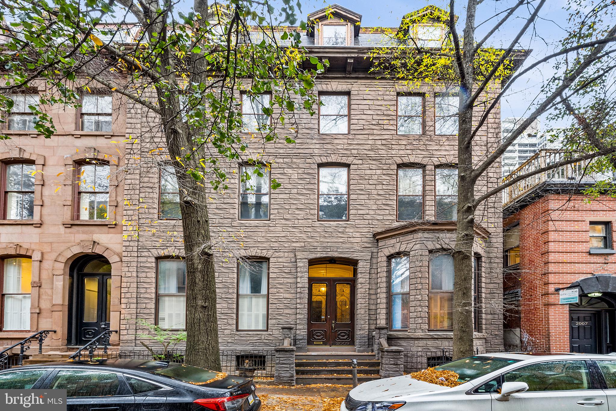 The dream has finally arrived. Just steps from iconic Rittenhouse Square, this expansive, first floor condo is more than a home - it’s a muse, a place to experience. Set within a historic condo building (only 3 units!), this expansive residence at 2009 Spruce St offers the rare gift of scale and flexibility.  With over 2,100 sqft above ground and an additional 1,700 sqft of finished lower-level space, the home effortlessly adapts - with room for a luxurious residence, inspiring work space, and creative studio. From the moment you enter, you’re greeted by soaring 13-foot ceilings, fluted columns, and exquisite historic detail. Color, texture, and thoughtful design abound: from custom window treatments to bespoke built-ins by Philadelphia Woodworking Company. The lighting is curated featuring Lindsey Adelman, Tom Dixon, Flos, and Arteriors. Designer-selected wallpapers by Brunschwig & Fils, Cole & Son, and Phillip Jeffries add layers of elegance and whimsy throughout. The entryway welcomes you with a built-in coat closet and an extended foyer or breakfast nook shining with periwinkle millwork and custom storage. The living room is a showstopper, complete with herringbone inlay flooring and intricate plasterwork - perfect for quiet mornings and lively evenings. Follow the brass railing up into the dining room, a mirrored and luminous space made for hosting unforgettable meals, with easy access to the skylit kitchen. The kitchen offers abundant cabinetry, new appliances, and updated countertops. Completing this wing of the home is a versatile guest room or office, with an en-suite bath and dressing area; ideal for visitors or a home office. Down a meandering hallway, you’ll discover a more private wing with a primary suite. The bedroom easily accommodates a king bed, and is illuminated by a south-facing bay window. The full bathroom is adorned in cut marble, offering a shower/tub combination for everyday indulgence. From the primary hallway is a staircase to the lower level. This finished basement features an additional living room (think home gym, playroom, or media lounge), a full bathroom, and another bedroom or studio space - perfect for yoga, art, or guests. You’ll also find a wine cellar, ample storage, and dedicated laundry room, rounding out this incredibly functional home! Enjoy the ease of first-floor living with the security of condo ownership, all in one of Philadelphia’s most coveted neighborhoods. Step outside to the very best of Rittenhouse - Parc, Via Locusta, Trattoria Carina, charming cafés, boutiques, and the Schuylkill River Trail and Dog Park are all just moments away. Homes like this don’t come along often!