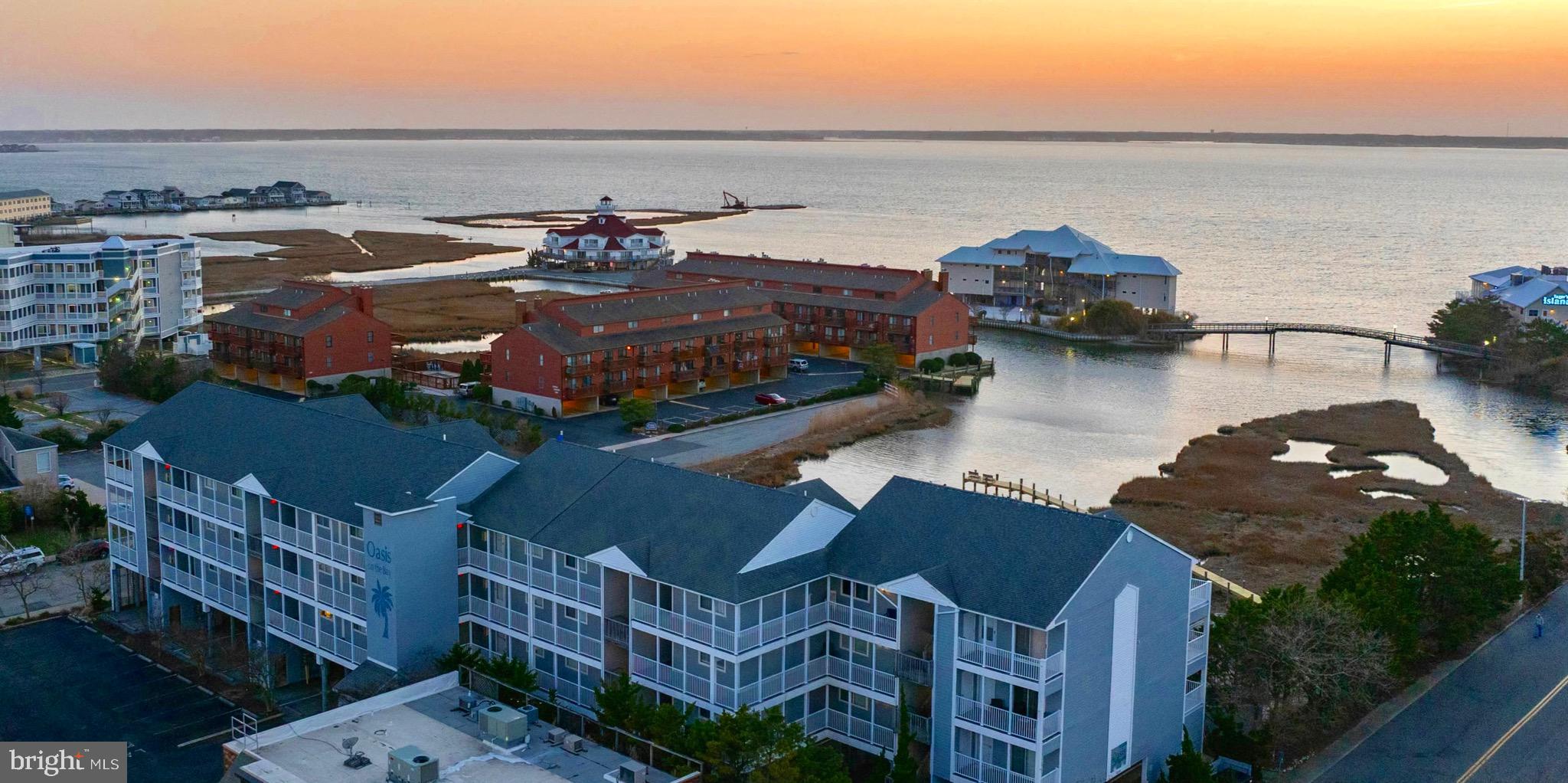Welcome to an exceptional bayfront residence offering refined coastal living at its finest. This two-bedroom, two full bath, top-floor, west-facing condo showcases unobstructed, panoramic views of the bay—an ever-changing backdrop of water, sky, and light that must be experienced to be fully appreciated.

From your private vantage point, indulge in Ocean City’s most breathtaking sunsets, where vibrant hues reflect endlessly across the water each evening. Perfectly positioned just two blocks from the ocean, this residence places you within a short stroll of Fager’s Island, along with an array of upscale dining, entertainment, and boutique shopping.

Meticulously maintained and never rented, this owner-occupied home reflects exceptional pride of ownership. Soaring vaulted ceilings and expansive glass invite an abundance of natural light, enhancing the open, airy ambiance while framing the surrounding waterfront scenery. Its top-floor positioning ensures both privacy and an added touch of southern exposure.

Both generously sized bedrooms serve as private retreats, each featuring its own en-suite bath and access to a private balcony—creating a true resort-style living experience.

Enhancing the lifestyle even further, this exclusive community offers private elevator access, a waterfront pool, and a dedicated pier—delivering the ultimate in convenience, leisure, and direct connection to the bay.

Whether envisioned as a private coastal escape or a high-performing investment, this residence offers strong rental potential in one of Ocean City’s most walkable and desirable locations.