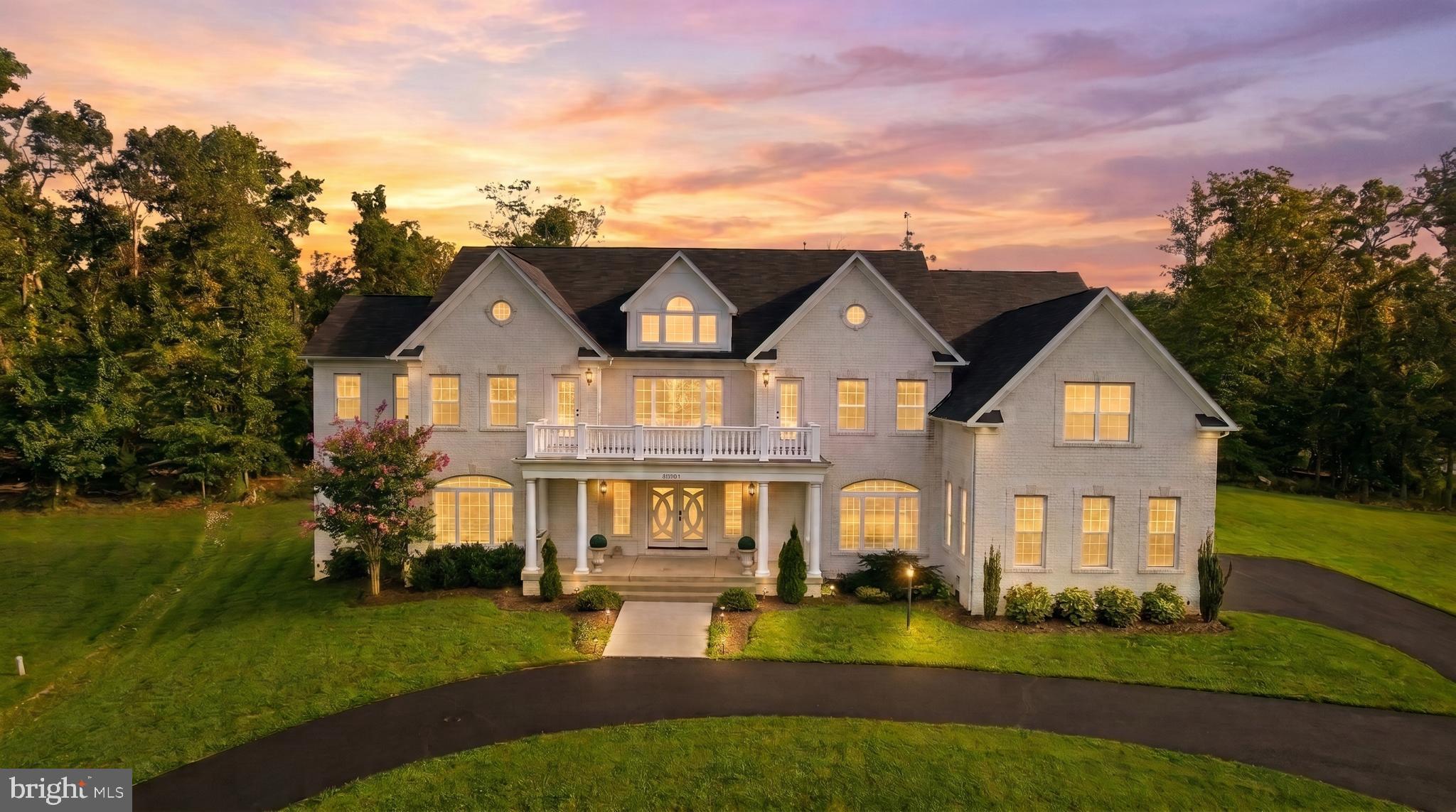 Commanding attention from its impressive 1.79-acre setting, this exceptional residence offers one of Fairfax County's most convenient locations. Commuters benefit from multiple routes to I-95 and quick access to the Fairfax County Parkway, keeping Fort Belvoir, Springfield, Alexandria, and Washington, D.C. all within easy reach. Nature lovers will love that the neighborhood sits less than a mile from the Potomac River, offering effortless access to waterside recreation and fishing just minutes from home. This rare blend of privacy, connectivity, and natural beauty sets the stage for a home that pairs timeless architecture with refined craftsmanship and thoughtfully designed living spaces. From the striking white brick exterior and custom portico to the beautifully appointed interiors beyond, every element reflects a commitment to quality, elegance, and modern functionality.

A dramatic two-story banquet hall sets the tone for the home's impressive scale and architectural detail. Dual angled oak staircases with decorative iron balusters frame the grand hall, while an upper-level gallery creates a striking overlook from above. A statement chandelier anchors the entry, complemented by custom double front entry doors with Low-E glass that provide a sophisticated first impression. Throughout the main level, thoughtful details including French doors, an arched decorative niche with accent lighting, and a double-step tray ceiling with integrated lighting add depth and character to the home's refined interiors.

The heart of the home offers an inviting blend of beauty and functionality, with a beautifully appointed kitchen featuring custom cabinetry, a large center island with step-down seating, and a premium 66-inch Electrolux refrigerator. The surrounding living spaces flow effortlessly together, including a bright sunroom and expansive gathering areas filled with natural light, creating a seamless environment for both everyday moments and special occasions.

Upstairs, the residence continues with thoughtfully designed private spaces featuring nine-foot bedroom ceilings, a refined hip roof design, and four secondary bedrooms enhanced by frosted interior doors. The primary suite provides a peaceful retreat with elegant finishes and a spa-inspired bath, offering a serene escape at the end of the day.

The fully finished lower level extends the home's living experience with a spacious recreation room, private office, media room, and a flexible entertaining space ready for a future wet bar or secondary kitchen. Whether used for relaxation, guests, hobbies, or additional workspace, this level provides exceptional flexibility to suit a variety of lifestyles.

Additional features include a three-car garage, a custom mudroom with beadboard backing, built-in bench seating, shelving, and coat hooks, along with two dedicated laundry areas located on both the main and upper levels for added convenience.

Surrounded by mature trees and peaceful open space, this remarkable residence offers an exceptional combination of architectural presence, custom craftsmanship, and modern convenience, creating a home that feels both timeless and distinctly personal.