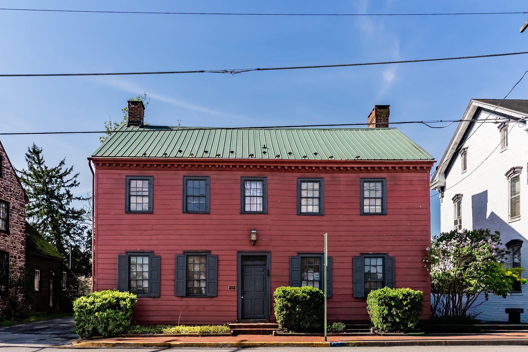 This charming well-maintained circa 1769 home, half timbered construction, seamlessly blends historic character with modern comforts. Spanning 1,872 sq. ft. , the interior boasts solid yellow pine hardwood floors and a traditional floor plan that invites warmth and togetherness. This center hall Georgian with the heart of the home features a cozy living room with fireplace.  The country kitchen with a pantry is fully equipped!  Enjoy gatherings in the dining area, enhanced by built-ins and elegant chair railings. Two spacious 2nd level bedrooms include an inviting primary bedroom with a dedicated private full bath that offers a tranquil retreat and another 2nd full bath for guests.  The finished attic can serve as a 3rd bedroom or hobby/craft or a play room.  Four wood-burning fireplaces, all recently cleaned, and each with unique mantels, create cozy nooks for relaxation. Outside, the property is set on a generous 0.24-acre lot, featuring a brick sidewalk that enhance the neighborhood's charm. You'll appreciate the longevity and peace of mind having a metal roof.   A livery stable in the rear of the property that was used as a gunsmith shop, antique shop and garage with off-street parking for four vehicles, convenience is at your doorstep. Located in a quaint small town community, residents enjoy easy access to local parks, schools, and public services, and community events, fostering a sense of belonging and make this a wonderful place to call home. Experience the perfect blend of history, comfort, and community in this delightful residence.  Call Today!