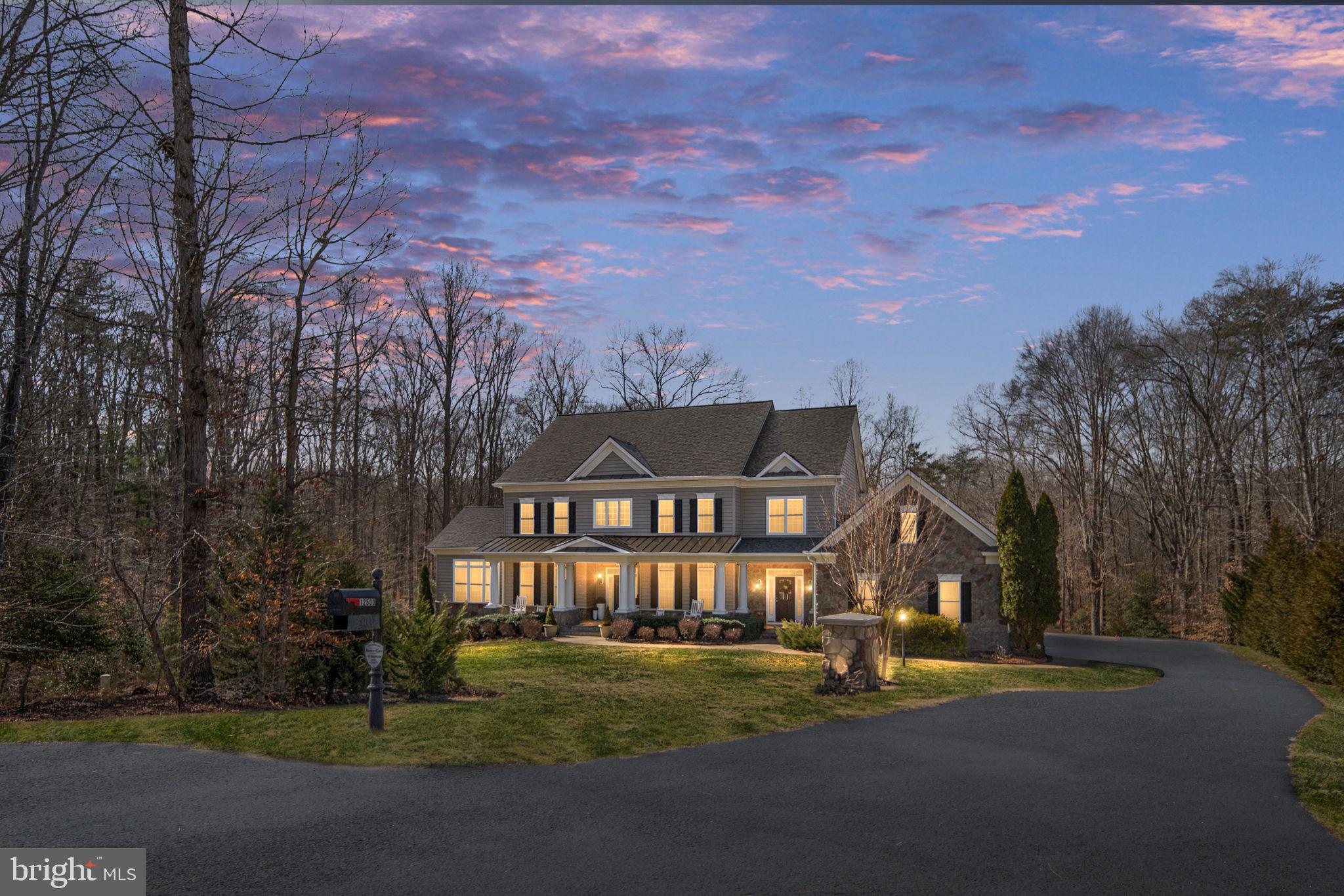 NEW PRICE + MOTIVATED SELLERS — NOW OFFERED AT $1,199,000! This extraordinary private estate offers nearly 8,000 finished square feet of refined living on 4.5 serene acres — where luxury, privacy, and exceptional value come together.

From the moment you arrive, the inviting front porch sets the tone for this peaceful retreat, designed for quiet mornings and relaxed evenings surrounded by nature and privacy.

Inside, a grand foyer welcomes you with timeless character and impressive scale. Rich hardwood flooring flows throughout the main level, leading into a thoughtfully designed gourmet kitchen featuring gas cooking, granite countertops, built-in appliances, and beautifully appointed cabinetry. The adjacent sunroom, filled with natural light and finished with elegant tile flooring, creates the perfect setting for morning coffee or casual gatherings.

The family room is both warm and dramatic, anchored by a striking stone gas fireplace and expansive windows that flood the home with natural light.

A private main-level guest suite provides flexibility and convenience for visitors or multigenerational living.
Upstairs, you’ll find four generously sized secondary bedrooms, including a Jack-and-Jill bath, along with a luxurious primary suite designed as a true retreat. The primary suite features custom built-in his-and-hers closets and an atmosphere of comfort and sophistication.

The fully finished walk-out lower level expands the living experience even further. Designed for entertaining and relaxation, it includes a sixth bedroom, upgraded full bath, impressive bar area, expansive recreation and lounge spaces, and a dedicated theater room — ideal for hosting, game nights, or private movie screenings.
Outside, the 4.5-acre setting provides exceptional privacy and endless possibilities to create your own outdoor oasis. The covered deck is enhanced with built-in surround sound speakers, creating the perfect backdrop for entertaining or unwinding in a peaceful setting.

Additional upgrades include a new roof, whole-house natural gas generator, whole-house water filtration system, and water softener system — offering peace of mind, efficiency, and comfort year-round.
Ideally situated with convenient access to I-95, Quantico, Fort Belvoir, Washington, D.C., the VRE, shopping, and dining, this estate perfectly balances luxury living with commuter practicality.

For qualified buyers, sellers may consider contributing toward an interest rate buy-down with a strong offer and favorable terms — creating an opportunity for added monthly payment savings while securing this exceptional property.

This is more than a home — it’s a lifestyle.