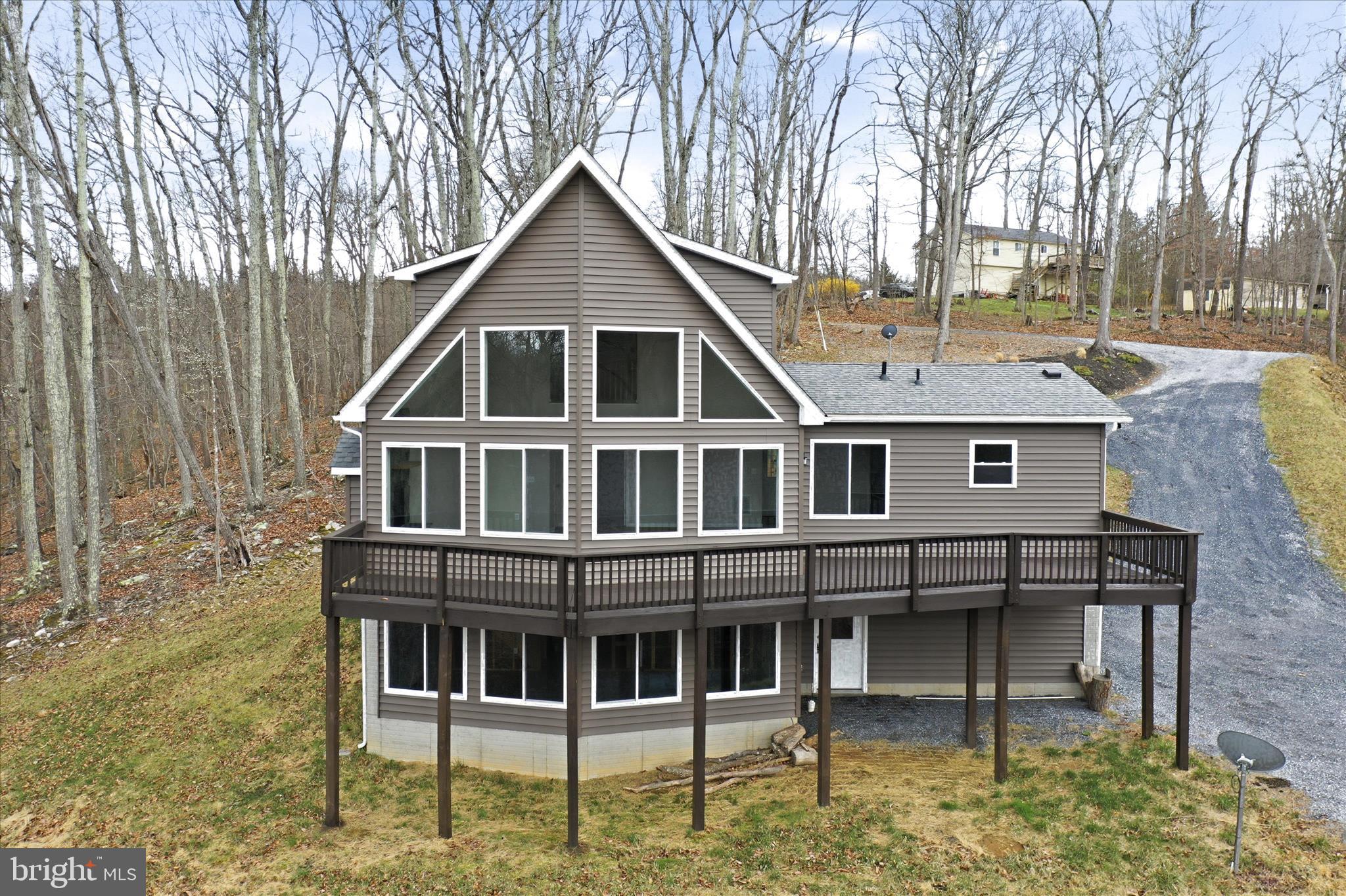 Tucked into 1.4 wooded acres in the Apple Mountain Lake community, this chalet-style retreat delivers the kind of mountain escape that’s increasingly hard to find — and even harder to leave. Built in 2022, the three-bedroom, three-bath home brings together modern construction and natural surroundings without sacrificing either.

Inside, vaulted ceilings and a wall of windows draw the outside in, while a stone fireplace anchors the great room as a natural gathering space in every season. The kitchen carries the same thoughtful finish work — granite countertops, clean cabinetry — that runs throughout. With three full baths and well-proportioned bedrooms, the layout works equally well for a full-time household, a rotating cast of weekend guests, or a short-term rental setup.

The 1.4-acre lot provides genuine privacy and a wooded buffer that signals mountain getaway the moment you arrive. A deck extends the living space outdoors, where the tree canopy and Blue Ridge views set the tone. A garage rounds out the practical side of the package.

Apple Mountain Lake adds a layer that comparable properties simply can’t match — a residents-only lake with beach access, dock, and swimming, plus hiking trails winding through the surrounding landscape. Minutes from I-66, the property sits within easy reach of Front Royal, the Shenandoah Valley, and the DC metro corridor — a natural fit for remote workers, weekend buyers, and investors eyeing the area’s active short-term rental market.
1,668 sq ft · 3 bed · 3 bath · 1.4 acres · Built 2022
