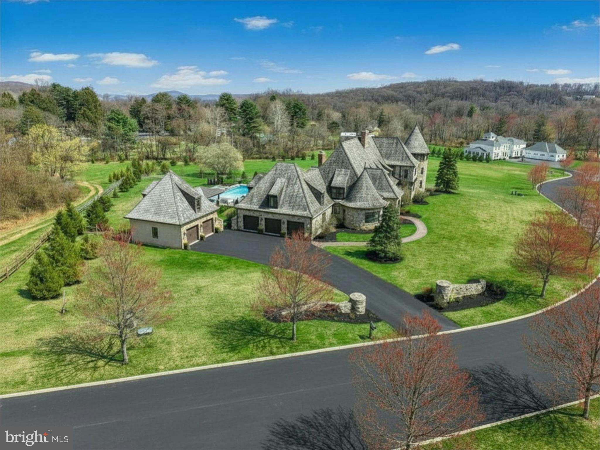 NEWLY PRICED...This magnificent home is evocative of the graceful splendor of old houses one might find nestled deep in the French countryside. Built by Myron Haydt for his personal residence in 2011, this 11,900 SQUARE FOOT HOME has an architectural style and interior design that is at once timeless and innovative. European influences are evident in the stunning FIELDSTONE AND BRICK EXTERIOR, DRAMATIC CEDAR SHAKE ROOFLINES,fieldstone and captivating turrets. Paver walkways and a welcoming drive lead to 5 car garaging as the first approach to this prestigious home, centered on 2.5 acres.
Inside, the home embodies a gentle blend of grace and subdued elegance. Rooms are bathed in light through oversized Pella windows and French doors. Ceilings are ten feet high on the main and lower levels and nine feet on the second. The many luxurious amenities include thick oak and marble floors, extra high baseboards, deep crown moldings and curved walls. There is a stunning kitchen, combining beauty and functionality, with a custom wood coffered ceiling, solid marble countertops, and stainless appliances. The adjacent breakfast nook has a vaulted ceiling and three walls of windows to let in natural light in every season. Nearby, the cozy family room has a wood-burning fireplace with marble surround, and two sets of French doors opening to the back yard and EXPANSIVE HEATED POOL, SPA, AND POOL HOUSE.
Spacious PRIMARY BEDROOM SUITES are found on both the FIRST FLOOR and SECOND FLOOR, welcoming use by extended families. These suites boast large windows and sumptuous baths appointed with marble floors, jetted tubs, walk-in showers, and custom vanities. The second floor primary suite boasts extraordinary size and comfort, with a gas lit fireplace and a curved stairway that takes you to a lofted room overlooking valley views and beckoning one to enjoy a private getaway or office retreat. A space for and ELEVATOR was designed during construction Three additional ensuite bedrooms and a first and second floor laundry room offer the amenities that one would expect from a home of this caliber.
A newly updated lower level includes a bar, WINE CELLAR, THEATRE ROOM, GYM, family room and wet bar, as well as a full bath with steam shower. The FIVE CAR GARAGING includes an attached 3-car garage and a heated 2-car detached garage with loft space, ready to be customized. The heated pool and spa, new pool house, and intricate paver patios are accessed from the sunroom and family room for intimate dinners under the stars or lively celebrations.
Melrose Manor is a modern estate with old-world charm, in a distinguished Saucon Valley neighborhood where shopping, dining, and entertainment venues are just minutes away.