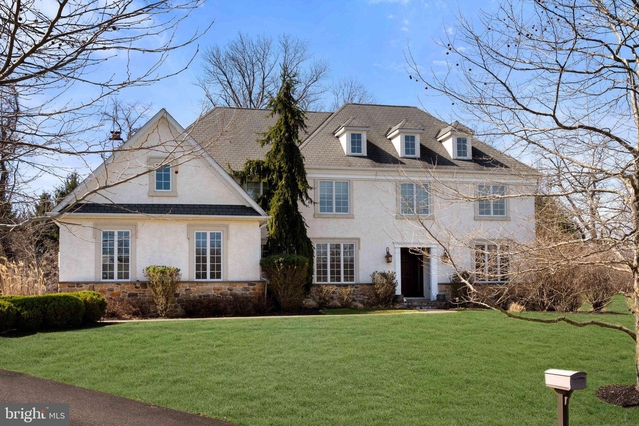 Welcome to 8 Quartermaster Lane, a semi-custom McBrick home designed for the way you actually live today. With a 3-car garage, refined finishes, and a layout that balances everyday comfort with effortless entertaining, this home delivers on every level. Step into a bright, welcoming foyer flanked by formal living and dining spaces with transom windows and a built-in bar with wine fridge, setting the tone right away. The kitchen is the centerpiece, featuring white cabinetry, a large island, farmhouse sink, stainless steel appliances, double ovens, gas cooktop, and a blend of marble and quartz countertops. It opens seamlessly to the breakfast area and out to a patio with a summer kitchen, perfect for hosting, grilling, and enjoying long evenings outdoors. The two-story family room is both dramatic and inviting, with a gas fireplace, custom built-ins, and natural light pouring in. A private office, laundry room, and powder room round out a main level that truly works for real life. Upstairs, the primary suite is a true retreat with two walk-in closets and a spa-like bath featuring a soaking tub, oversized shower, double vanities, and private water closet. Three additional bedrooms include a princess suite, offering flexibility for guests or multi-generational living. The finished basement adds even more usable space for a gym, media room, playroom, or additional office. Set in a sought-after Bucks County location close to shopping, dining, and major routes, this home offers the space, style, and convenience today’s buyers are looking for.