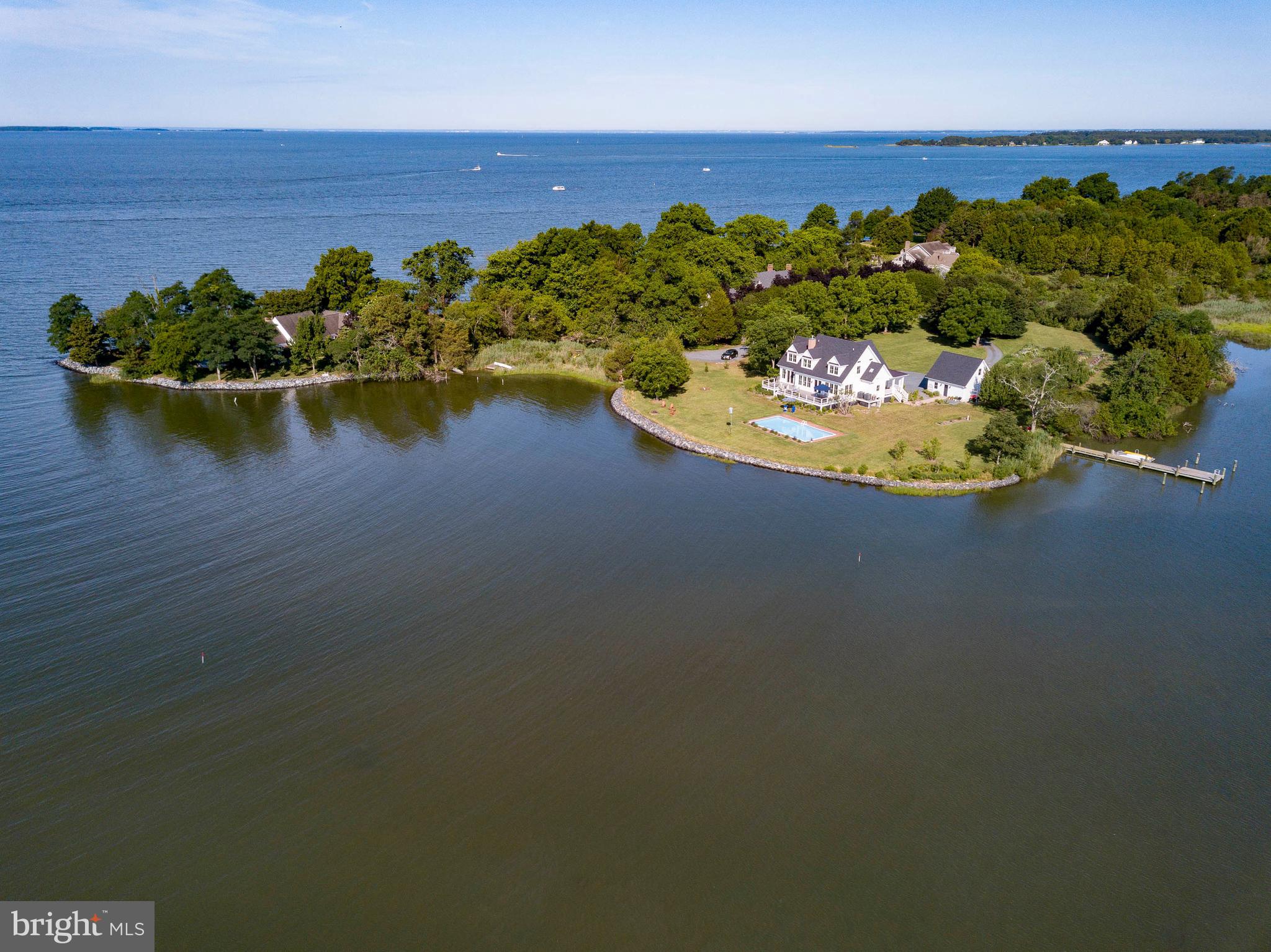 Set on a private point overlooking Boone Creek and the Choptank River in Oxford, this exceptional 4BR/2.5BA modern farmhouse offers panoramic water views and refined coastal living on 2.4 acres. Built in 2018, the home showcases high-end finishes, hardwood flooring throughout, and a light-filled, open design with walls of windows capturing the surrounding waterfront. A welcoming, expansive front porch introduces the main level, where the cathedral-ceiling living room with gas fireplace flows seamlessly into a gourmet kitchen with top-tier appliances—ideal for both everyday living and entertaining. The main-level primary suite enjoys water views and privacy, while the second level overlooks the living space below and features three additional bedrooms and a full hall bath. Outdoor amenities complete the offering, including a waterside deck, new gunite pool (Aqua Pool), private pier with two slips and floating dock, riprapped shoreline, detached two-car garage (transformed and finished into a large office), and beautifully landscaped grounds—perfectly capturing the relaxed elegance and timeless appeal of Eastern Shore living.