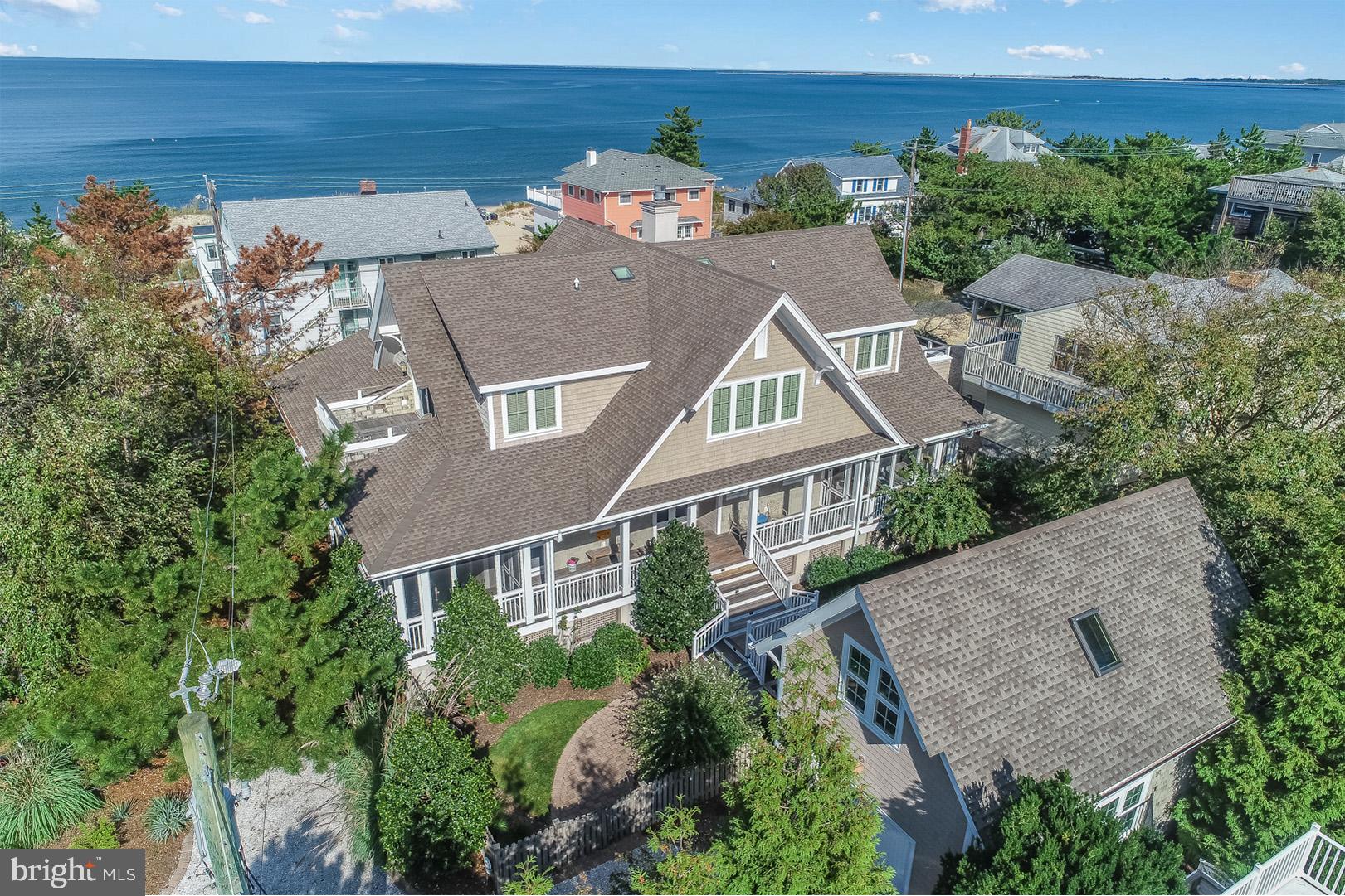 Welcome to 7 Indiana Avenue, an iconic Lewes Beach home.  This exquisite property was designed by the late Jay Dalgliesh of Dalgliesh Gilpin Paxton Architects of Charlottesville, VA.   Mr. Dalgliesh was a renowned Architect throughout the world and known for many esteemed projects such as The V House in Charlottesville, Virginia and Les Joiles Eaux in Mustique.  Recipient of many honors through the years, he was recently presented with the Milton Grigg Award by the American Institute of Architects. Mr. Dalgliesh’s life-long friendship with the homeowners granted him the ability to design a home based on their personal lifestyle.  To start, 7 Indiana was designed around the footprint of the original Lewes Beach cottage offering more flexibility in the size of the many outdoor and indoor living spaces.  Every angle of this custom home exudes coastal elegance.  The shingle style exterior featuring cedar shake siding, quintessential plantings and landscape, flagstone walkways, Honduran Mahogany doors and extensive porches and balconies create the most tranquil setting, a necessity for any coastal lifestyle.  Upon entry, you will be captivated by the Australian Cypress flooring which offers a rich color and texture in every room highlighted by the natural light from the plethora of windows.  The open floorplan is ideal for intimate gatherings with comfortable spaces for all, inclusive of a plantation room, dining area, and family room with a wood burning fireplace decorated with a custom mantle designed from reclaimed woods from the original UVA Rotunda.  The large kitchen is the heart of this home offering ample storage, a large island with a mahogany counter top, expansive breakfast bar featuring honed granite, stainless commercial grade appliances, and wet bar complete with a beverage and wine fridge.  The first-floor master suite offers the most relaxing environment featuring a reading nook, private screened porch, and beautiful spa like bath complete with a soaking tub and oversized glass shower.   The second level offers a cozy escape for guests, complete with three enormous guest suites and three private baths.  Two of the guest suites feature unique trundle style custom built beds, ideal for overflow company.  These rooms also feature private balconies offering tranquil bay views.  In addition, the second level living space is complete with a private balcony, gas fireplace and more views of the Delaware Bay.  Guests may never want to leave! 7 Indiana Avenue also features a large private rear yard complete with a grilling patio and outdoor shower.  As an oversized lot, this property offers great potential for a pool!  Like few beach homes, this property offers a spacious garage ideal for vehicle storage or beach toys, and a walk-up 2nd level that is roughed in for plumbing and electric.  This space is perfect for additional storage or simply drywall and finish as another guest suite, art studio, home office, workout room, or workshop.  The options are truly endless. You can be assured that no detail was overlooked in 7 Indiana and pride of ownership shows.  Conveniently located within steps to Lewes Beach, the Lewes Yacht Club, and Downtown Lewes amenities, this home truly leaves nothing to be desired event for the most discerning buyer!