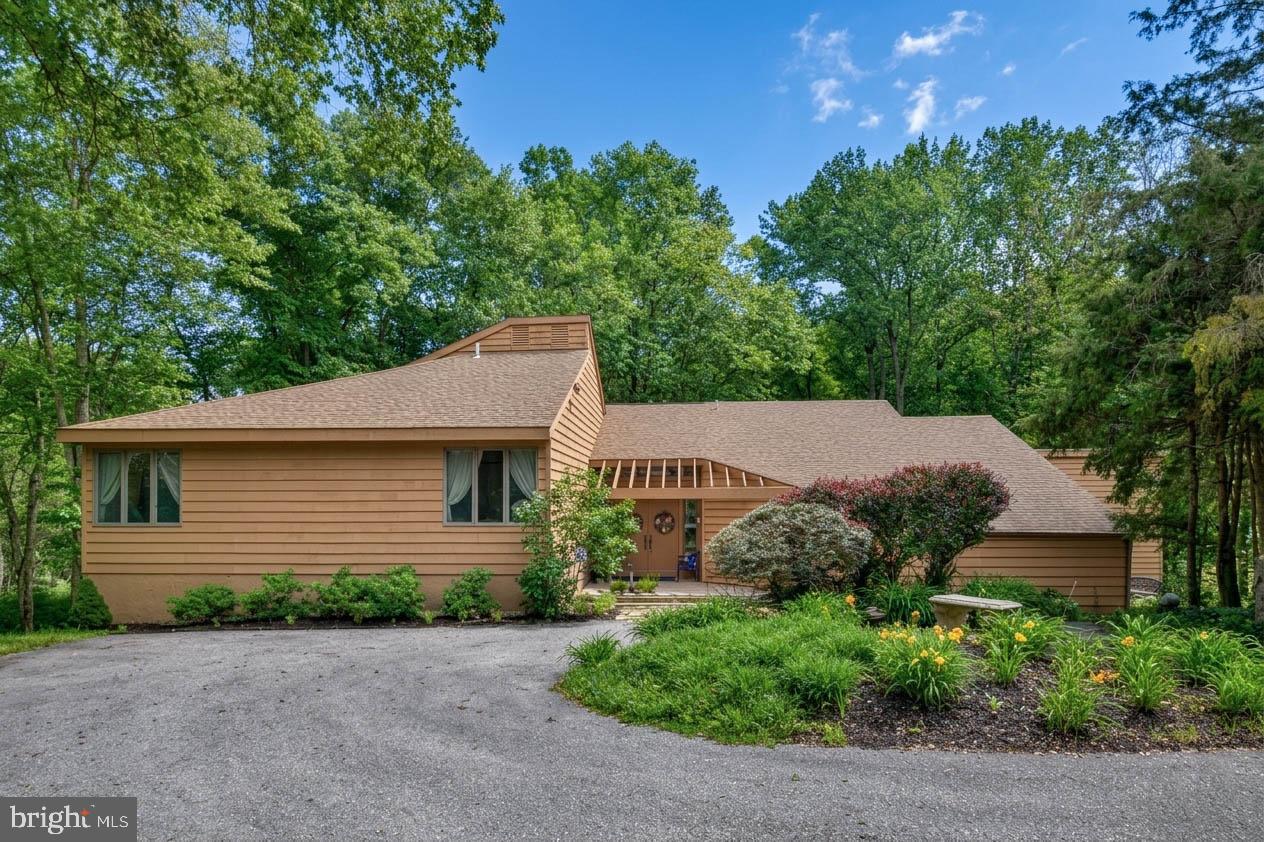 Nestled deep within a lush, wooded landscape, this stunning contemporary retreat offers the perfect blend of architectural character and natural serenity. Designed to bring the outdoors in, this exceptional four-bedroom, 2.1-bath custom home is perfectly situated on 5.73 private acres within the prestigious Unionville-Chadds Ford School District. Located on a quiet cul-de-sac in Delaware County, the property offers a lush, nature lover's entrance that leads into an inviting foyer with hardwood floors and soaring vaulted ceilings. The main level features a sunken living room anchored by a wood-burning fireplace and a wet bar, flowing effortlessly into a sun-drenched dining room. At the heart of the home, the kitchen boasts a center island, stainless steel appliances, and ample cabinetry, overlooking a morning room that transitions into a cozy family room with its own vaulted ceilings. Two separate entrances lead to a show-stopping sunroom, providing breathtaking views of the grounds and access to a wraparound deck that spans the length of the main living areas. The first-floor primary suite serves as a true retreat, offering vaulted ceilings, built-in walk-in closets, and a main bathroom equipped with a double vanity and jetted soaking tub. Upstairs, you will find three additional well-sized bedrooms and a full bathroom. The expansive acreage creates a private paradise complete with heavy landscaping and a peaceful creek at the base of the grounds, all while maintaining convenient access to major highways like Route 202 and Route 1. This is a rare opportunity to own a home that truly transcends the ordinary.