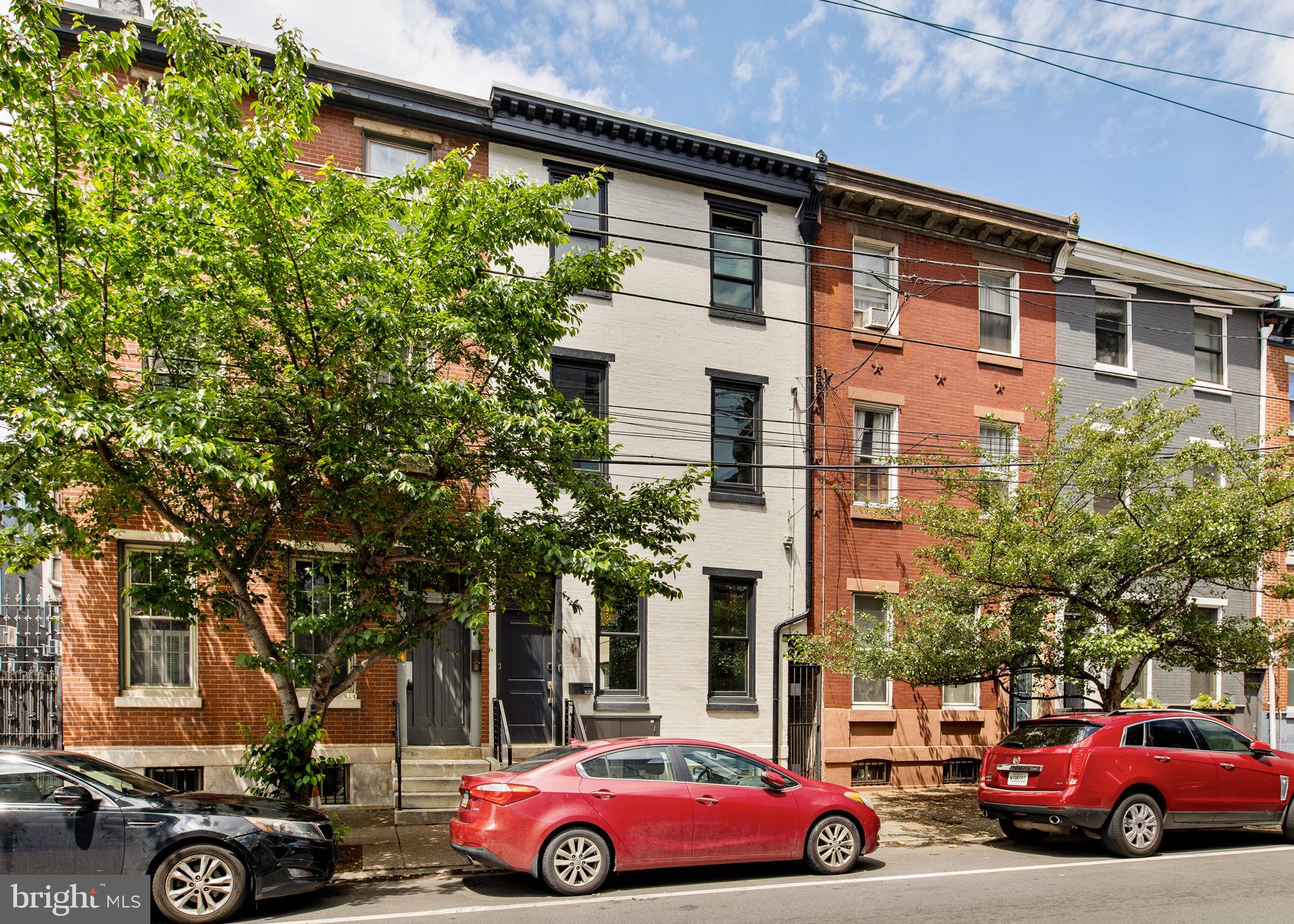 Welcome to 1012 N 5th Street — where historic character meets elevated modern living. This breathtaking, fully renovated 5-bedroom, 2.5-bathroom townhouse sits in the heart of Northern Liberties, offering approximately 3,218 square feet of thoughtfully restored interiors that celebrate the home's original craftsmanship while delivering every modern comfort. Soaring ceilings, oversized east-facing windows, rich hardwood floors, and an abundance of natural light set the tone from the moment you arrive. A gracious entry vestibule welcomes you into a grand, sun-drenched living room — expansive in scale, flexible in use, and stunning as a first impression. The space can easily accommodate both formal living and dining, offering the kind of optionality rarely found at this size. A sweeping curved staircase serves as the historic centerpiece, drawing you through to the chef's kitchen and breakfast room beyond. The kitchen is a true showpiece — outfitted with premium appliances, custom cabinetry, and expansive countertops that balance form and function effortlessly. Open to the breakfast area (currently serving as the primary dining space), the room is anchored by a striking limited-edition Shinola pendant lighting set that elevates the entire space. A chic powder room and thoughtfully designed mudroom complete the main level.
Step outside to a professionally redesigned private oasis. Stretching approximately 34 feet deep and nearly 600 square feet, this extraordinary outdoor space was thoughtfully reimagined from the ground up — and it shows. Elegant Carpinus betulus 'Frans Fontaine' columnar trees and Limelight hydrangeas add seasonal color and lush texture. A dedicated vegetable garden and curated rose garden speak to the level of intention behind every planting decision. Raised planters, a wood-burning fireplace, and generous entertaining areas complete the picture. Whether it's morning coffee, al fresco dinners, or a quiet evening by the fire, this garden is a true extension of the home. The entire second floor is devoted to rest and rejuvenation. The primary suite is exceptional in size — a hall spa-inspired bathroom features a freestanding soaking tub and an oversized steam shower wrapped in penny tile with a built-in bench. A separate walk-in closet, practically bedroom-sized, adds a level of luxury rarely seen at this price point. A generous guest bedroom and a laundry room that redefines the standard — with full-size front-loading machines, an oversized utility sink, extensive storage, and a built-in steamer column — complete the floor. The third floor is as versatile as it is impressive. A spacious secondary family room — or optional fifth bedroom — comes complete with a wet bar, Bosch dishwasher, and dual refrigerator drawers, making it a natural fit for entertaining, hosting guests, or creating a private lounge. A beautifully appointed full hall bathroom with a striking exposed brick accent wall adds warmth and character to the floor. Two additional generously sized bedrooms round out the level, including a stunning front room with eastern exposure and soaring cathedral ceilings. A large, high-ceilinged unfinished basement offers a blank canvas ready for your vision — whether that's a home gym, media room, playroom, wine cellar, or expanded storage. The home sits on a massive 18 x 110-foot lot — an exceptional footprint for a Northern Liberties townhouse, offering both the outdoor depth and interior scale that define this property.

Dual-zone, high-velocity central air and radiant heat

1012 n 5t has been outfitted with an exceptional array of smart home and premium features designed for modern living at its finest. 

Ideally situated in the heart of Northern Liberties, 1015 N 5th places you moments from Liberty Lands Park, Little City Montessori, Cruz Playground, and The Piazza. The sellers rent 2 parking spaces from PPA a stones through away. Inquire about potentially transferring.