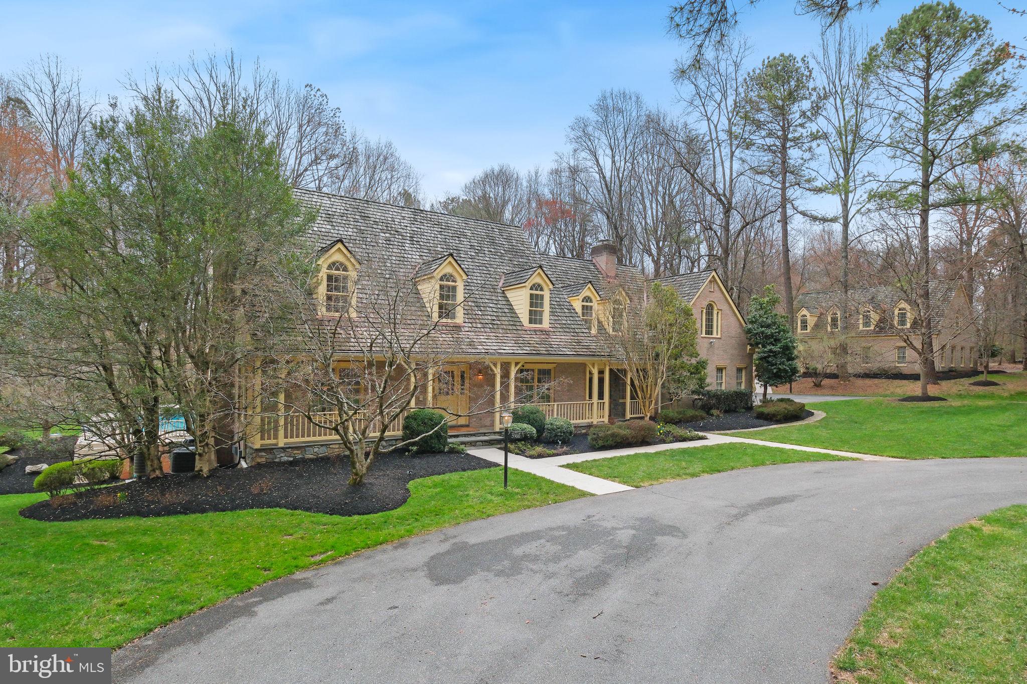 AS-IS PROPERTY - Tucked away at the end of a private drive on over 11 acres, 5900 Serenity Lane is an estate-like property featuring an elegant brick Colonial, an expansive backyard retreat with a heated pool, and a detached 2,312 sq ft building that includes a 3-car garage and a full 1,054 sq ft apartment above.
The main home offers 4 levels of finished space with 6,387 sq ft, 7 bedrooms, 5 full baths, and 2 half baths. One of the many highlights of the property is the backyard retreat, showcased by a heated inground pool with a raised spa and waterfall spillover, gazebo, large patio, and abundant green space framed by mature trees. Car enthusiasts will love the detached 3-car garage with car lifts, built-in storage, and a half bath. A bonus apartment above offers an additional bedroom, full bath, kitchenette, and living room—perfect as a rental or guest suite. A circular drive, flagstone patio, and covered porch welcome you into the main home with a dramatic two-story entry. Design details and updates include refinished hardwood floors, new carpet, fresh paint, crown molding, a back staircase, a finished basement, a finished fourth level, 5 fireplaces, multiple sets of French doors, oversized windows, a skylight, wall sconces, built-ins, abundant closet space, professional landscaping, and more. The oversized kitchen features dual refrigerators, a cooktop, range, peninsula island with breakfast bar, granite countertops, generous cabinetry, a built-in workstation, and a pantry. The breakfast area offers space for a full table and is filled with natural light from a large bay window and a door opening to the patio and backyard. The adjacent family room, accessible from both the kitchen and main hallway, is framed by French doors on either side that open to the front porch and back patio, and features side-by-side wood-burning fireplaces set within a rustic stone accent wall. The formal living room offers the third main level fireplace, while the formal dining room is finished with wainscoting and a large bay window. A main-level office with a wall of floor-to-ceiling built-in bookshelves, a powder room, and a mudroom with side entry and access to the attached 2-car garage complete the main level. Upstairs, you’ll find 5 bedrooms and 4 full bathrooms. The owner’s suite boasts a fireplace, cathedral ceilings, and a private balcony with tranquil views of the backyard. The generous en-suite bath includes a soaking tub and walk-in shower. The finished fourth level provides a private suite with a sitting area, bedroom, and full bathroom. This flexible space is ideal as a second primary suite, guest suite, second office, playroom, or studio. The walk-up lower level offers a sizable recreation room featuring the fifth fireplace, a half bath, bonus room, and abundant storage space. Ideally located with easy access to shopping, dining, entertainment, and major commuter routes, the property is also close to parks, recreational amenities, and golf courses. And backs up to park land with easy access to miles of trails and a nature center. Top-rated Montgomery County schools add to the appeal.