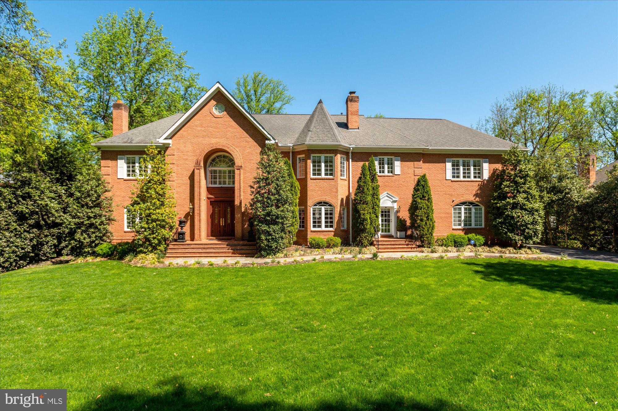 Prestigiously perched on nearly an acre in the coveted McLean neighborhood of Langley Forest, 7024 Benjamin Street is a custom-built home with palatial scale exuding opulence at every turn. Presenting an extravagant oasis just outside our nation’s capital, manicured lawns, lush gardens, and mature trees encompass the home’s stately brick façade for premiere privacy. The residence offers an expansive floor plan spanning 11,850 total SF across 3 Levels, 8 Bedrooms, and 8.5 Baths. Elegant design notes extend throughout the residence’s perfectly appointed interiors to include magnificent millwork, cathedral ceilings, and endless windows flooding the interiors with natural light and providing stunning views of the landscaped grounds, creating a harmonious blend of the property’s indoor and outdoor offerings. 
A circular, two-story foyer with dual stairway offers a grand welcome to this estate and is flanked by the formal Living and Dining Rooms, each complete with their own Wood-Burning Fireplace. Providing optimal Main Level living, the entry floor showcases an expansive Primary Suite complete with two walk-in closets and spa-like bathroom, as well as a generous Great Room featuring a gas fireplace, cathedral ceilings and direct access to the home’s spacious Rear Deck. The Gourmet Kitchen features stainless steel appliances, endless counterspace, large butler’s pantry, and wet bar. An adjacent Breakfast Room features an additional gas fireplace and deck access. Idyllic al fresco dining can be enjoyed on the home’s spacious rear Deck overlooking lush grounds or the Gazebo located in the heart of the rear yard’s pristine gardens. A Laundry Room with exterior egress and access to the home’s 3-Car Garage completes the Main Level’s offerings. 
Accessible by grand stairway, the guest quarters are primarily located on the Upper Level and include a second, expansive Primary Suite with oversized walk-in closet, sitting room, fireplace and spa bath, 4 additional Bedrooms and 3 Baths, including a recently renovated Jack and Jill Bath. The rooftop terrace is the true showstopper of the Upper Level, providing panoramic views of the manicured acre lot and Langley Forest community. 
The walkout Lower Level offers ample space for informal living with a Recreation Room, Billiards Room, Den, and fully renovated Catering Kitchen! Office space, 2 en-suite Bedrooms, and abundant storage space are also located on the Lower Level. Showcasing a seamless synthesis of effortless and luxurious grand scale living, both indoors and out, 7024 Benjamin Street is an enviable Langley Forest estate sure to please the most discerning of buyers.
