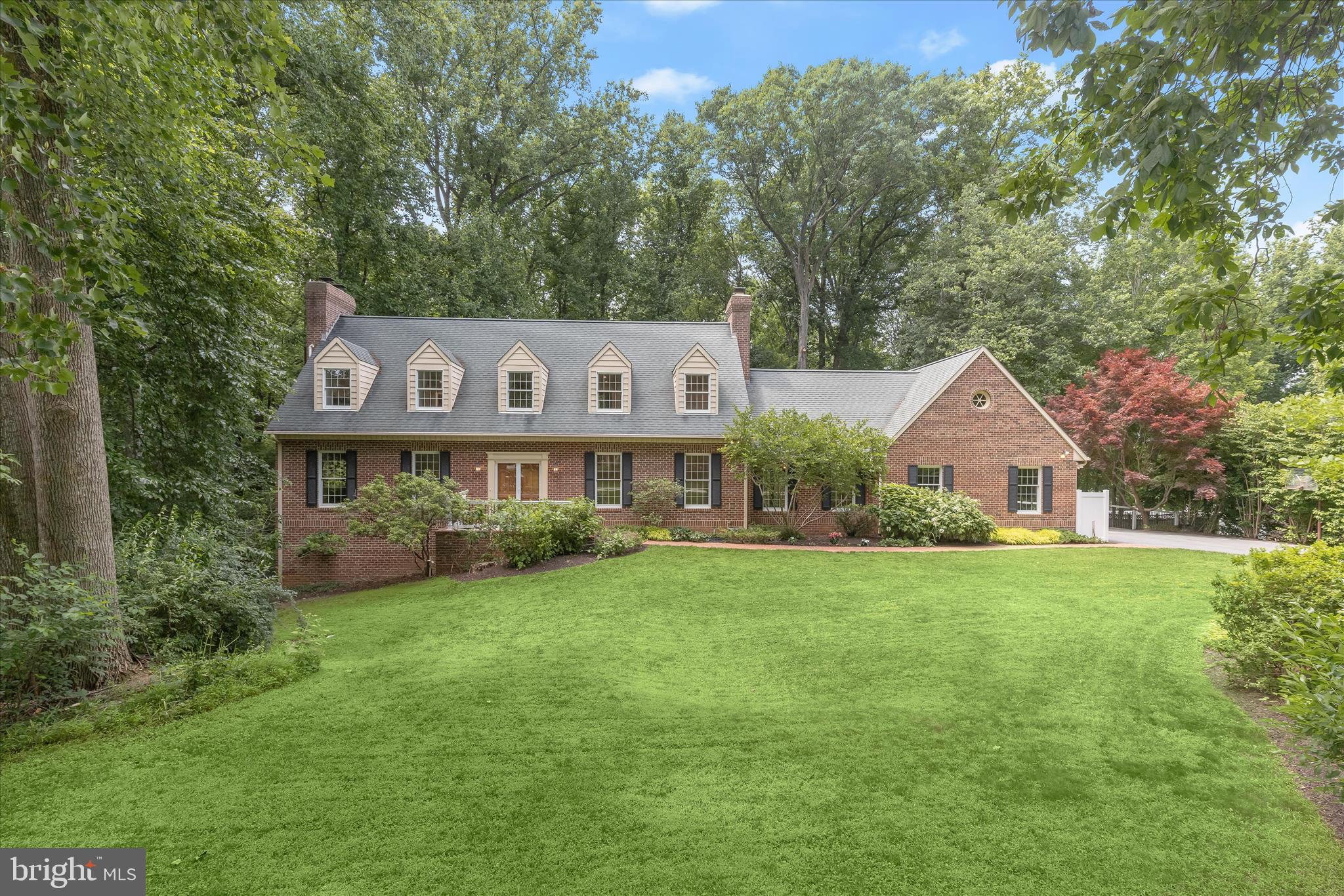 Spacious and beautifully maintained Cape Cod nestled on a premium 2.1-acre lot in the coveted Highland Lake community. Set back from the road and surrounded by nature, this all-brick home offers over 4,000 square feet of living space, 5 bedrooms, 4 full baths, two brand-new decks, and an exceptional setting backing to woods extending well beyond the fenced area with a peaceful stream running behind the property.  The welcoming interior features a slate tile foyer, formal living and dining rooms adorned with rich recently refinished hardwood floors, elegant dental crown molding, and a classic wood-burning fireplace. The spacious kitchen is designed for both everyday living and entertaining, offering abundant wood cabinetry, a peninsula island with glass cooktop, and a bright breakfast area overlooking the scenic backyard.  The expansive family room showcases hardwood flooring and a stunning wall-to-wall brick fireplace, and entrance to the deck, creating a warm and inviting gathering space.   A convenient main-level bedroom and full bath with  updated vanity and mirror and lighting, along with a laundry room complete the main level.  Upstairs, the oversized primary suite serves as a private retreat with a walk-in closet, updated vanity dressing area, and a beautifully updated en-suite bath featuring Schluter heated floors and heated towel bar, decorative tile inlay, and a frameless glass shower with three shower heads, including a luxurious rainfall shower. Two additional bedrooms, all with hardwood flooring, and a full hall bath complete the upper level. The walkout lower level provides incredible flexibility with a private guest or in-law suite featuring a living area, full kitchen, a bedroom and a full bath, and bonus room, ideal for extended family, guests, or multi-generational living.  Enjoy outdoor living at its finest from the two decks and fenced yard overlooking the wooded surroundings and tranquil stream. Residents of Highland Lake enjoy sought-after community amenities including lake access, picnic areas, and scenic hiking trails. Recent updates include: new hot water heater 2023, HVAC 2022 and 40+ yr composite roof in 2005.
