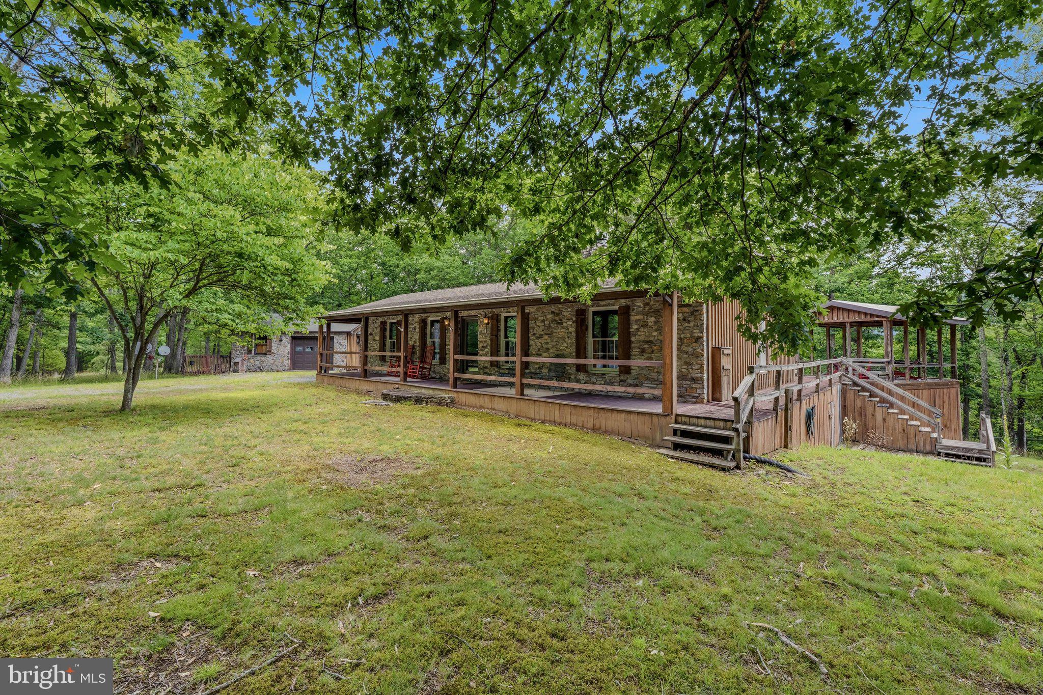 Escape to peaceful country living in this charming 2-bedroom, 2-bath rancher on 5 very private acres in a gated water-access community. This home features classic stone and wood siding, a wraparound deck, and a beautiful gazebo perfect for outdoor entertaining.

Inside, enjoy single-level living with a nice floorplan, stone double sided fireplace in living room and primary suite, a partially finished basement offering extra space for hobbies or storage. Whole house generator conveys.  A detached garage outfitted as a workshop, plus an attached screened porch and carport, provide convenience and versatility.

Only 15 mins to downtown Berkeley Springs and @ 2 hrs from Baltimore and DC.
A rare blend of privacy, craftsmanship, and community amenities—your ideal retreat awaits!
