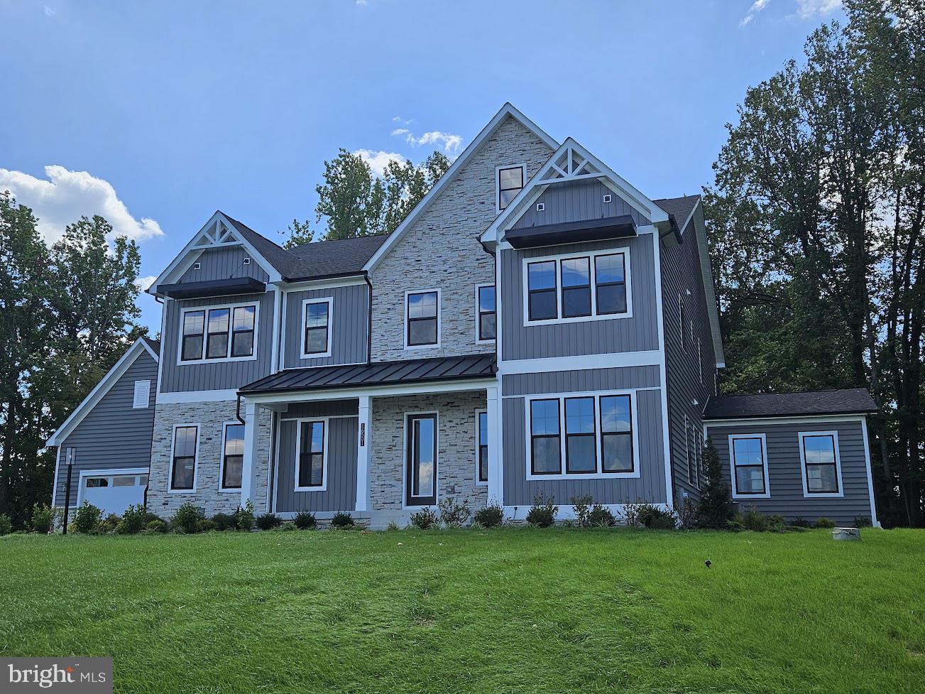 STUNNING WOODED VIEWS! Meet the Hampton II by D.R. Horton EMERALD. This home includes 6 bedrooms/6.5 baths/4-car garage with finished basement and main level suite. This exquisite home is positioned in a cul-de-sac and sits on a serene 2.13-acre wooded homesite offering unparalleled privacy. The contemporary exterior elevation is complete stone, siding, covered porch, sleek black trimmed windows, and metal roof. The elegant 2-story foyer will sweep you off your feet along with soaring 10 Ft. main level ceilings. A flex room to use as you would like would make a perfect home office. The dining room will provide you years of exciting entertainment. The rich oak staircase and owner entry are adjacent to the foyer. Walk into the Chef’s Kitchen with high end Kitchen Aid appliances to include a French door refrigerator, dishwasher, 5-burner 36” gas cooktop, 30” double oven, hood vent and built-in microwave. An abundance of cabinet space to include a built-in pantry with roll-out shelves and over-sized island with cabinetry on all sides. A breakfast nook is positioned to the side. The kitchen, breakfast nook and family room provide plenty of space and airiness for everyday living as this is the hub of the home. Contemporary grey cabinets are throughout the kitchen with gleaming quartz counters. Easy to maintain solid surface flooring is throughout the main living area. The soaring 10-foot ceilings allow for 8-foot doors throughout the first floor. Enjoy wooded views from the double 8-foot sliding glass doors and a 60” Crave gas fireplace for a cozy day. The solarium is a sanctuary of tranquility filled with bountiful light. From the owner entry a main level bedroom with private bath and walk-in closet is positioned. The owner entry provides plenty of space for a drop-zone. The 4-car garage includes an EV plug along with door openers and exterior key pads for convenience. A grand oak staircase with metal balusters lead to the upper level with a primary suite, 4 bedrooms, laundry room and plentiful storage. The primary suite is spacious with room for a sitting area with 2 separate walk-in closets- no need for sharing! Enter the opulent primary bath through double doors and view the glass walk-through ceramic tile shower and soaking tub as a focal point. Separate comfort height vanities with an abundance of storage and quartz counters are adjacent with plenty of floor space. 3 additional rooms grace the upper level of this home, each with sizeable walk-in closets and private baths. All secondary baths include ceramic tile, upgraded soft-close cabinets and quartz counters. For convenience, the laundry room is on the bedroom level with cabinets, utility sink and a linen closet for storage. The walk-out basement provides plenty of natural lighting and is complete with a recreation room, bedroom, a full bath, and additional finished area below the solarium- perfect for a home theater. Additional finished storage closets are in the basement. The unfinished portion allows for storage or can be finished in the future for additional rooms! Stay connected to your new home through our smart home package to include door camera, z-wave door lock, z-wave thermostat, IQ Panel and Echo pop. Light switches throughout are by Deako- plug and play modular switches to easily add motion sensors or dimmer switches on your own. Many area conveniences include the new South Lake shopping center. Perfect for commuting this location has quick easy access to Rt. 301, Rt. 50 and Rt. 4 to Washington, DC, Annapolis, or Baltimore.