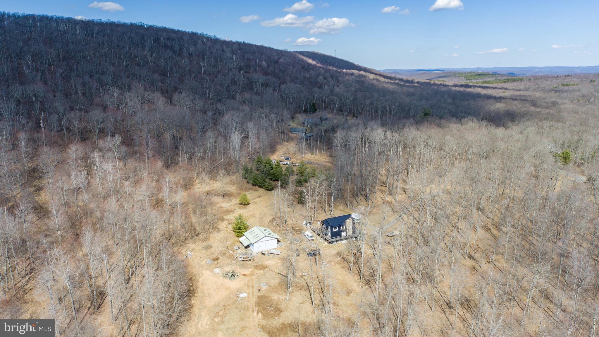 Over 150 acres of private mountain land. Thick woods, wide views, and total peace. The home is fully renovated—new siding, metal roof, and trex decking are wrapped all around. Inside, everything shines. Modern kitchen. Brand new appliances. Bar top seating for the crew. A native stone fireplace that roars. Extra wood stove for those deep winter nights. Three bedrooms. Three tiled baths. The cozy den upstairs provides additional living space. All new floors, paint, and fixtures. Downstairs is a giant two-car garage with space to grow. 32 x 32 Pole barn out back with room for toys, tools, or a full-blown shop. This is where rugged meets refined. Luxury without the noise... and just 15 minutes from Deep Creek Lake. Don't miss this once-in-a-lifetime opportunity - Call today to schedule your private showing!