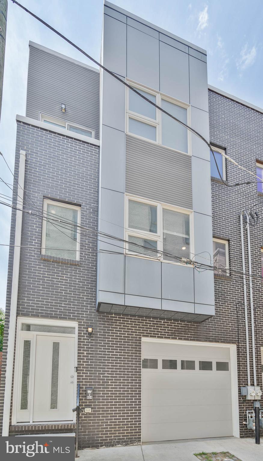 Hidden away on a quiet, cobblestone alley in the heart of Philly's vibrant Northern Liberties neighborhood, you'll discover 854 N Leithgow St. This modern 3-story home offers 3 bedroom suites with 4.5 total bathrooms, a finished basement, a private patio, a roof deck, and a sought-after 1-car garage. A towering brick facade greets you out front. Inside, you're welcomed by a foyer with access to the garage. Gleaming hardwood floors stretch down the hall into a large, sunlit bedroom suite with an attached full bathroom, a walk-in closet, and French doors that can be left open as an additional living space or closed for a private office. A pair of sliding doors open to the secluded rear patio, perfect for hosting barbecues or relaxing alone. The finished basement provides another bonus space, ideal for a gym, playroom, or home theater, along with a full bathroom, laundry, and storage. Upstairs, the huge, open main level is bright and airy, with lots of natural light pouring in. There's tons of space to hang out in the living room at the front. The kitchen and dining area has white shaker cabinetry, natural stone counters, stainless steel appliances, a tile backsplash, an island with seating, a pantry, a half bathroom, and a Juliet balcony. The home's third floor has a large primary suite with lots of bright windows, a walk-in closet, and a luxurious attached bathroom featuring a double vanity, a glass-enclosed shower, and sleek tile. A second bedroom suite with a full bathroom completes the level. A final staircase with a terrace at its base leads to the expansive roof deck that's sure to be a popular place to enjoy time with family and friends while admiring the skyline views. 854 N Leithgow St's fantastic location earns a Walk Score of 88! The tax abatement started in 2017. Top-rated restaurants, friendly shops, and lively entertainment fill the surrounding blocks. Playful parks are close, and neighboring Fishtown has lots more to explore. There's also easy access to I-676, I-95, and South Jersey. Schedule your showing today!
