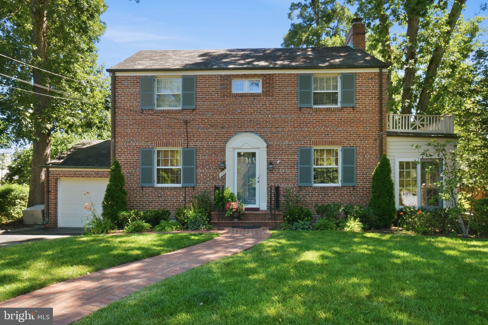Elegant three-bedroom, three-bathroom Colonial features over 2,000 sq. ft. of finished living space across three levels. A brick walkway leads to a welcoming front portico and an inviting center-hall foyer. Gorgeous, freshly refinished hardwood floors shine throughout this renovated 1940 all-brick beauty. A traditional floor plan includes a spacious dining room, a formal living room with a fireplace and a wall of built-in shelving, and a well-appointed chef’s kitchen. Kitchen features abundant white cabinetry, granite countertops, stainless-steel appliances, a food pantry, eat-in breakfast bar and overlooks the backyard. Main level also includes a coat closet and a beautiful sunroom with three walls of windows. Upper level with three bedrooms and two bathrooms, including an en-suite. The lower level is fully finished with a recreation room, built-in shelving, a laundry room, an alternate fourth bedroom, storage and utility space. Beautiful backyard includes both a covered and uncovered deck, a pergola, and immaculate mature landscaping. Irrigation system, an attached one-car garage and driveway parking for an additional vehicle. Abundant upgrades and recent renovations – this one is move-in ready!