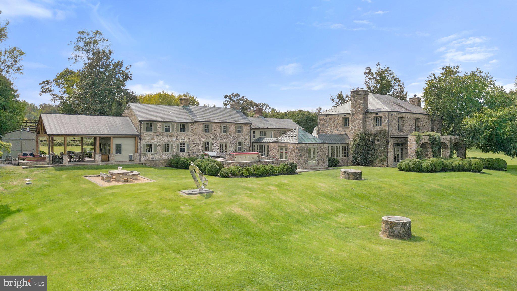 Littleton Farm comprises over 153 spectacular acres with a serene four-acre lake, two smaller ponds and Beaverdam Creek meandering through the property. Tucked in the southwest corner of Loudoun County and situated at the foothills of the Blue Ridge Mountains the property offers spectacular views. Considered the heart of horse and hunt country, this estate is situated within the famed Piedmont Hunt territory and provides tremendous ride-out. Anchoring the farm is the over 14,000 square foot French country fieldstone residence which presents comfortable living and entertaining spaces with soaring ceilings, unique and inviting gathering areas and breathtaking views of the lake and rolling hills. The oldest part of the home is believed to be well over 50 years old, but in the year 2000 a tremendous addition designed by well-known local architect Errol Adels was added. For the car enthusiasts there two detached garages with 4 and 6-bays. Within the main home are 7 bedrooms, 6 full bathrooms, and 2 half baths. Upon entry, you are welcomed into the incredible living room with 14 foot ceilings with exposed wood beams, two fireplaces with limestone hearths imported from France and large tile limestone floors. Three French doors open to a flagstone terrace with views of the lake and the impeccable grounds. From the living room, one can enter the guest wing or the main living wing through sun-drenched hallways. The guest wing offers 3 bedrooms and 2 full baths. The main living wing of the home was the original stone farmhouse and includes a cozy wood paneled library with a fireplace, a formal dining room, a commercial-grade kitchen with a breakfast area and the mudroom/pantry. Directly above the dining and kitchen area are the laundry room and two guest bedroom suites with their own full bathrooms. Above the library is a separate set of stairs to a one-bedroom guest suite with a full bath. Relax and unwind in the primary suite showcasing sweeping views from two sets of French doors and numerous windows. Located above the large living room, this private space provides all the luxuries expected in a primary suite – a sitting area, fireplace, separate walk-in closet with ample built-ins, full bathroom with dual vanities, separate soaking tub and standing shower, as well as a home office. To complete the house, family and friends will love the extravagant family room and home theater located on the finished lower level. From a separate outside entrance one can access the over 2000+ bottle wine cellar. A few hundred feet from the main home is the 60-foot saltwater pool and a pool house complete with a steam room, large gym, guest bedroom and full bath. There are two additional guest suites with their own full bathrooms and separate entrances located above the 4-bay car garage near the pool house.  Other farm outbuildings include: 2 horse barns (12 stall barn and 17 stall barn), 1 machine shed, 4 run-in sheds, a 100 x 200 riding arena, 3 and 4 board fenced pastures with Nelson automatic waterers. The property is protected by a VOF open space easement.  Littleton Farm is conveniently located 38 miles from Washington Dulles International Airport and 52 miles from our nation's capital. Be sure to watch the video!