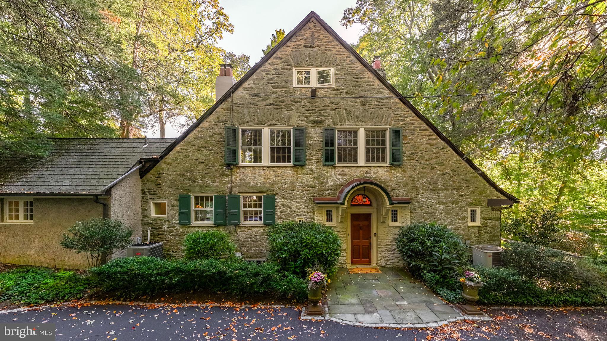 Welcome to a Fabulous English Country Garden Estate on the Main Line! This stunning home on 1.18 Acres is nestled in a private, wooded area of Lower Merion, yet is within walking distance to the train station.

Built in 1912 by Allen Evans, the architect behind the Merion Cricket Club in Haverford, this home’s front exterior was inspired by the designs of Edwin Lutyens, a leading architect of English country houses in the UK. Constructed from large stones, the home boasts impressively thick walls and has been preserved in line with its historic character. The property features a grand wood burning fireplace in the great hall, four other fireplaces, a remodeled kitchen, six bedrooms, four and a half bathrooms, beautiful hardwood floors, two staircases (one off the kitchen and one off the hallway), two porches, a terrace, a balcony, a detached two-car garage, a shed, and charming gardens with a creek running through the property. The property has a common right-of-way to access the back path leading to Suburban Square, making it very walkable; and the train station, with direct route to Center City Phila and New York. The school district is Lower Merion.

As you enter through the front door, charmingly tucked away on the side of the home, you are welcomed by a striking Mercer-tiled hallway. This elegant entryway features a series of double French doors that lead to two covered porches and the serene south garden. To the right, the garden study awaits, with a gas log fireplace and exterior door to the gardens. On the left, just up a few steps, you'll find a powder room and a spacious kitchen, complete with a Sub-Zero refrigerator and granite countertops. The kitchen seamlessly connects to a comfortable family room, with convenient access to the garage and back gardens.

Adjacent to the kitchen, and accessible from both the hall and the kitchen, is the formal dining room, featuring a gas-log fireplace and three large twelve-pane windows that offer picturesque views of the back terrace and gardens. At the far end of the hallway, lies the magnificent great room, perfect for both relaxation and entertaining, featuring a stunning Mercer-tiled fireplace, french doors opening to the front and side gardens, and a large stone bay alcove with charming leaded windows.

The second floor offers three en-suites, two wood-burning fireplaces, an office/den and plenty of closet space, including walk-ins. The primary suite includes a luxurious bathroom with heated floors, a sitting area, and a balcony large enough to accommodate a table and chairs. The third floor features three additional bedrooms, a full bathroom and access to the attic.  The basement includes a laundry room, full house  storage, and potential space for a wine cellar.  

This incredible house is a true masterpiece, combining historic charm with modern amenities in a breathtaking setting!