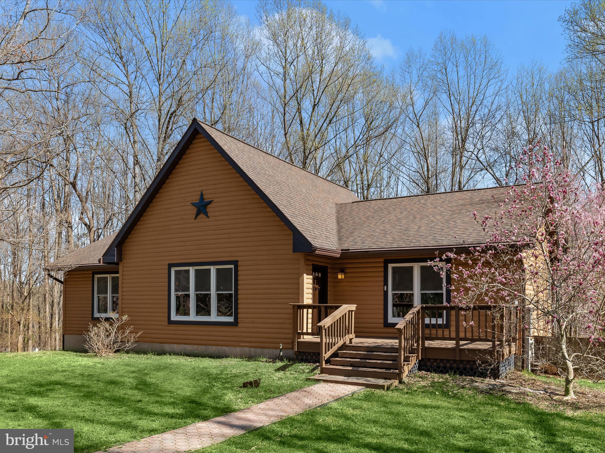 Escape to your own secluded oasis with this stunning, log cabin-style home, nestled on 3.5 wooded acres offering an in-ground heated saltwater pool, soaring cathedral ceiling with a loft in the great room, and a walkout basement with a bath rough-in, just waiting for your customization. Thoughtfully updated, this home boasts a brand-new remodeled kitchen, roof 2017, 8" gutters with leaf guards, HVAC 2019, 22KW whole-house generator in 2022, new windows and sliding door 2023, hot water tank 2023, flooring, newly refinished cedar log exterior, and more!  The cathedral ceiling in the main living area creates a breathtaking sense of space, while the rich, wood  walls and ceiling enhance the home's rustic charm. Overlooking this impressive space is a loft, adding a touch of character and versatility.  The chef's kitchen has been exquisitely remodeled with pristine white quartz countertops, soft-close cabinetry, and stainless steel appliances, including a dual oven glass-top range. Flanked by the dining and breakfast rooms, this space seamlessly flows to the expansive deck, perfect for outdoor dining and entertaining.  The entry-level primary suite is a tranquil retreat, offering a vaulted ceiling, a walk-through closet, and a beautifully updated en suite bath featuring a glass-enclosed shower with decorative tile inlay and dual shower heads. Two additional spacious bedrooms and a well-appointed hall bathroom and laundry room complete this effortless one-level living.  Unleash your creativity in the walkout basement, which includes a bath rough-in, ready to be customized to your exact needs.  Step outside to embrace the serene beauty of nature, whether lounging on the expansive deck or taking a refreshing dip in the heated saltwater pool, surrounded by a lush tree-lined backdrop.  While offering complete privacy, this home is also conveniently located near major commuter routes I-70, Route 40, and Route 32, with easy access to shopping, dining, and entertainment.  Don’t miss this rare opportunity to own a private retreat that seamlessly blends rustic elegance with modern luxury—schedule your showing today!