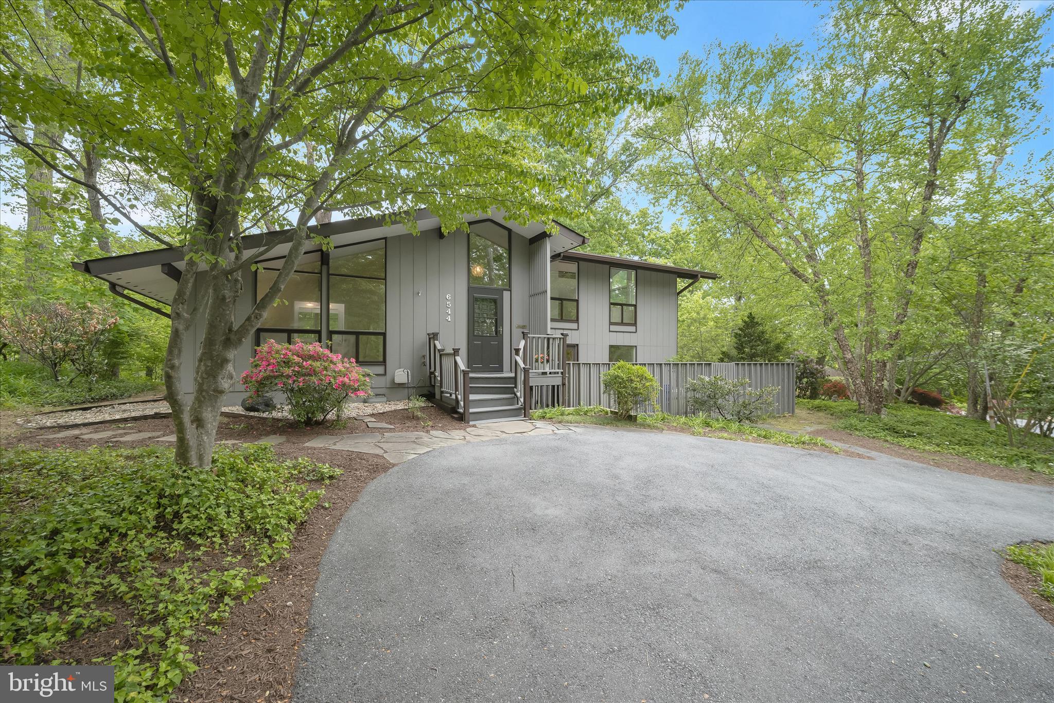 Perched atop a hill on a beautiful wooded lot, this sun-filled mid-century modern in Glen Echo Heights offers three bedrooms and two-and-a-half bathrooms in an ideal Bethesda location with easy access to downtown DC, Virginia, and beyond. A circular driveway and a charming front entrance create a welcoming arrival, surrounded by mature landscaping, lush greenery, and ample garden space.

A dramatic two-story foyer filled with natural light sets the tone for the home’s airy, architectural feel. The upper-level living room is bright and inviting, featuring vaulted and beamed ceilings, oversized windows, and a built-in bar, with glass doors opening to a patio overlooking the serene setting. The updated kitchen is thoughtfully designed with double ovens, a pantry, a Bosch dishwasher, and skylights that flood the space with sunlight, with direct access to one of the many decks for effortless everyday living. The open family room is both warm and functional, offering hardwood floors, vaulted ceilings with exposed beams, custom built-ins, and a gas fireplace with a striking stone mantle. Oversized glass doors lead to a multi-level deck and patio, creating a seamless indoor-outdoor flow that is perfect for entertaining. Throughout the home, generous storage and oversized closets add superb convenience.

The main-level primary suite provides a peaceful retreat with wood floors, a spacious closet plus an additional large walk-in closet, and a well-appointed bath with a dual vanity, a separate water closet with tub, and charming angled ceilings with beam accents. 

On the lower level, you’ll find ample sunlight, two generous bedrooms, a renovated hall bathroom, and a spacious laundry room with a utility sink and exterior access. A bonus mudroom space provides additional storage and flexibility as well as access to the yard, bringing the beautiful setting inside. The lowest level features a utility and storage room for convenience. Ideally located in the Whitman cluster, this home offers a seamless blend of contemporary architecture and functional spaces, providing an exceptional move-in-ready opportunity in the heart of Bethesda!