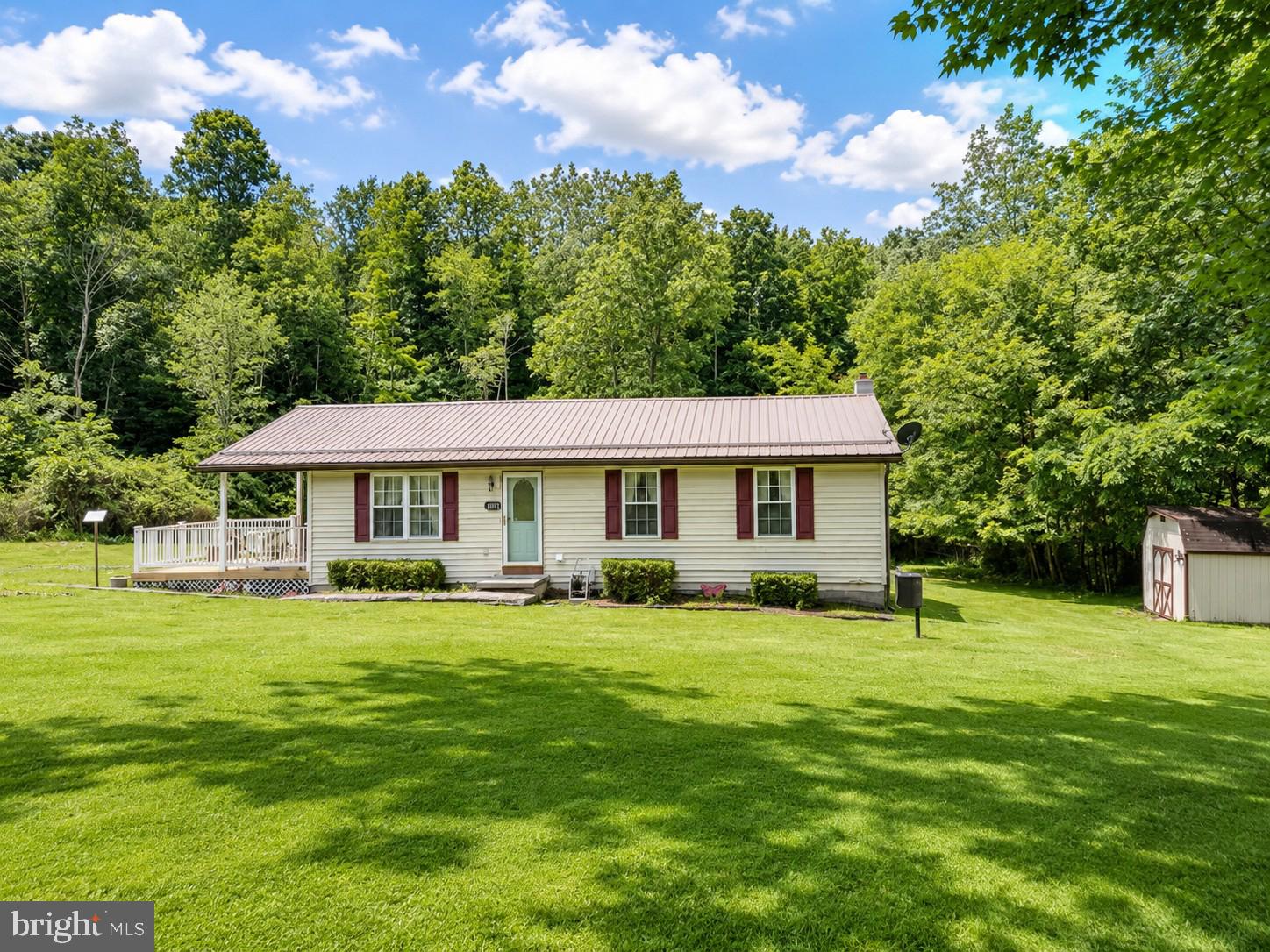 Escape to your own private retreat! Nestled on 2 scenic acres and backing to peaceful woods, this charming 3-bedroom, 1-bath rancher offers the perfect blend of comfort, privacy, and country living. Step inside to find an inviting eat-in kitchen, updated replacement windows, a durable metal roof, and an efficient heat pump with central air to keep you comfortable in every season. The spacious bathroom features a walk-in shower, and you'll love the convenience of main-level laundry hookups in the third bedroom, with additional hookups available in the full unfinished basement. The expansive basement offers endless potential—create the workshop, home gym, recreation room, or additional living space you've always wanted. A propane-powered whole-house generator provides added peace of mind, while the two-car carport offers plenty of covered parking. Outside is where this property truly shines! Relax with your morning coffee or host summer cookouts on the spacious deck overlooking your private backyard and beautiful wooded views. With room to roam, space to garden, entertain, or simply enjoy the tranquility of nature, this property delivers the lifestyle you've been dreaming of. Whether you're looking for your first home, a peaceful place to downsize, or your own slice of country paradise, this move-in-ready rancher is ready to welcome you home! *Some Photos are Virtually Staged*
