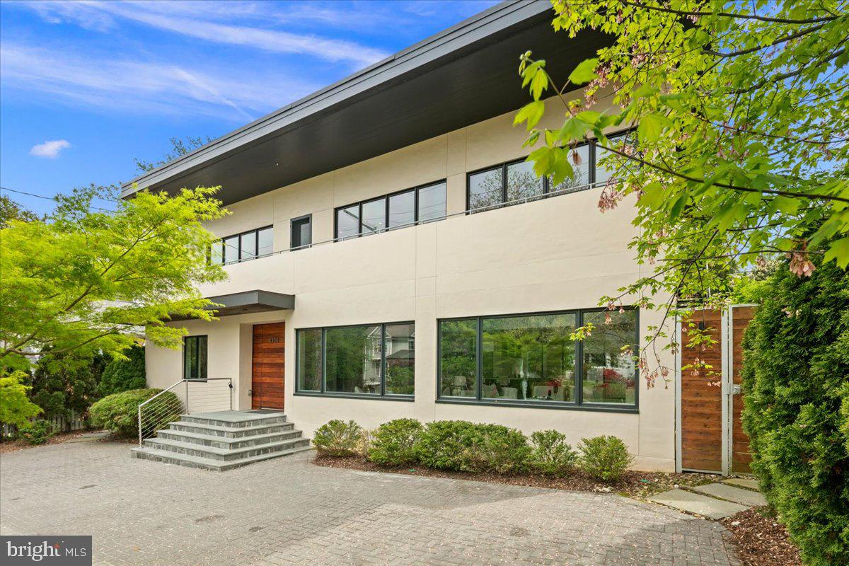 Welcome home to a dramatic yet inviting residence located on a tree-lined street in the heart of Bethesda. This rare offering masterfully blends modern design with warm livability. Soaring ceilings and abundant natural light fill every room, creating an open, airy environment equally suited to quiet everyday living and spirited entertaining. The seamless open-concept floor plan is an entertainer's dream and a canvas purpose-built for art collectors looking to showcase their finest works.

Stepping inside, you are immediately welcomed by soaring ceilings, generous natural light, and open-concept living at its finest. At the heart of the home, the chef's kitchen is outfitted for the most discerning cook. A full suite of Miele and KitchenAid appliances, a dedicated prep sink, and a built-in wine refrigerator deliver professional-grade performance with effortless style, making it as functional as it is beautiful. A large living room with a gas fireplace offers a warm, inviting setting to begin an evening of entertaining, while the generous dining room at the rear of the home opens through double doors to the lush landscaped backyard, seamlessly connecting indoor and outdoor living.

Completing the main level are two spacious bedrooms served by a full bathroom, alongside a main-level primary suite featuring dual built-in closets and a beautifully appointed en-suite bathroom with Porcelanosa tile, a soaking tub, separate walk-in shower, dual sinks, and a private water closet. Step outside through the primary suite's sliding doors to your own lush, private garden sanctuary. For added convenience, the washer and dryer are also located on this level.

Upstairs, the family room offers an additional gathering space anchored by a stunning double-sided fireplace, a warm focal point that bridges rooms and elevates the home's sense of comfort and sophistication. A third full bathroom is conveniently located just off the family room. The upper-level primary suite is a true retreat, complete with a spacious en-suite bathroom featuring Porcelanosa tile, double sinks, a large walk-in shower and private outdoor space, offering a peaceful sanctuary above the treetops.

Outside, lush, mature landscaping frames a beautifully layered experience across multiple levels, creating a serene oasis ideal for morning coffee, al fresco dining, or simply unwinding in nature. A welcoming rounded driveway accommodates two to three vehicles with gracious ease.

Ideally positioned just minutes from the vibrant dining and shopping of Bethesda Row, the National Institutes of Health, and Metro access for effortless entry into Washington, D.C. — this address delivers the very best of suburban living with city connectivity at your doorstep. Nature lovers will appreciate easy access to the Bethesda Trolley Trail, a 4.5-mile paved path weaving past Bethesda Row and Glen Echo Park, as well as Lynnbrook Park, Battery Lane Park, Caroline Freeland Urban Park, and Elm Street Urban Park, all just minutes away.