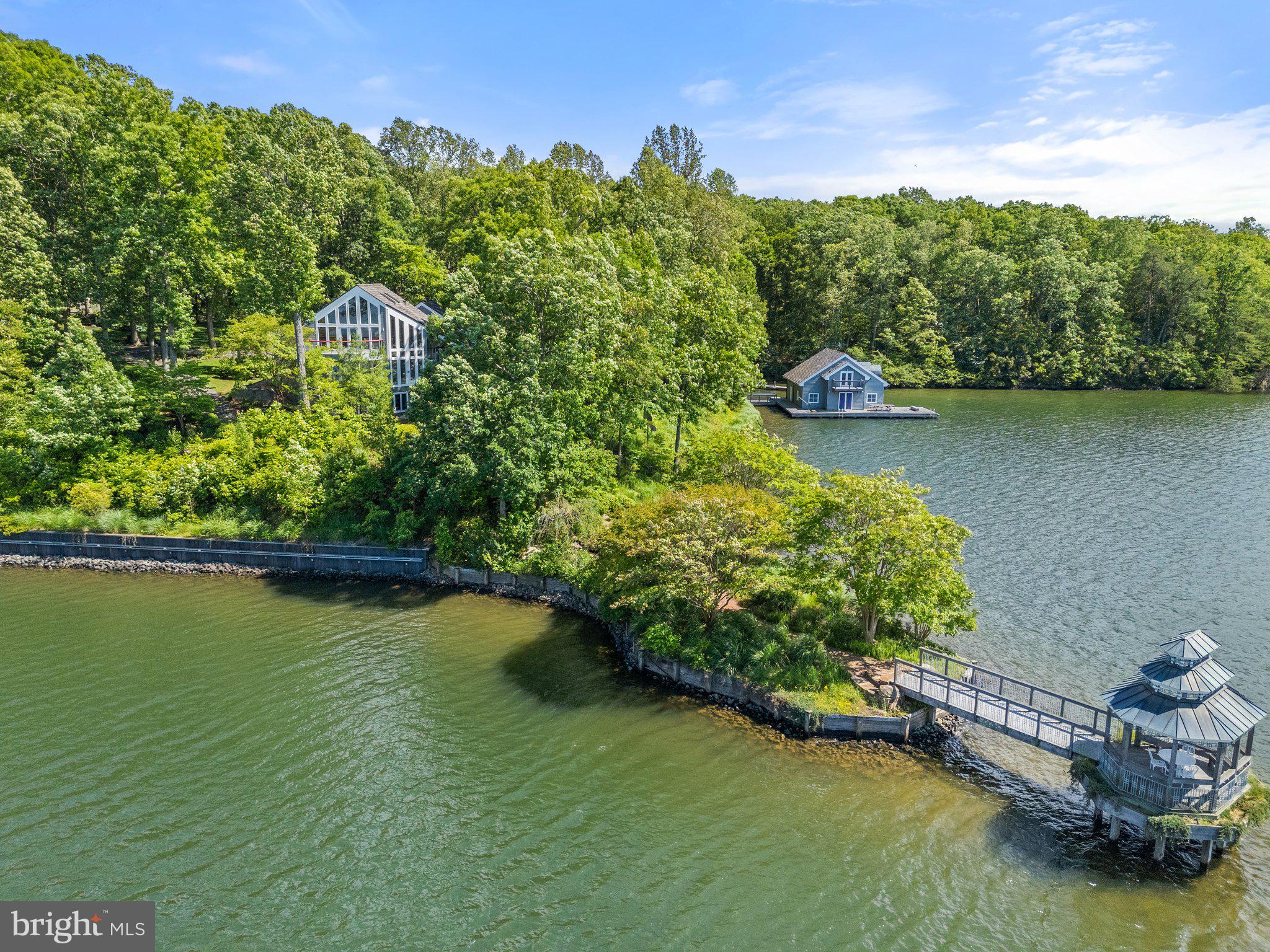 Now featuring a $500,000 price improvement, this one-of-a-kind Lake Anna estate offers 1,147 feet of private shoreline on 8.66 acres across three parcels. A rare combination of privacy, scale, and waterfront prestige, the custom-built residence is perfectly suited for luxury entertaining, private dock access, and resort-style outdoor living—an exceptional opportunity to own a legacy property.

Set behind a private gate, a sweeping asphalt drive and flagstone motor court lead you to the heart of the estate: a stunning 8,200+ square-foot main residence, surrounded by panoramic lake views and lush landscaping. In total, the property includes over 12,262 square feet under roof, featuring a spacious three-car garage, detached lakeview office suite, workshop, guest studio, and a fully appointed boathouse.

Main Residence:  Inside, the main home features four luxurious bedroom suites, each with a private balcony overlooking the water. There are five full baths and two half baths, each finished with timeless materials and upscale details.

A dramatic foyer welcomes you with immediate, sweeping views of Lake Anna through expansive windows. The great room is a showstopper, featuring vaulted ceilings, a wood-burning fireplace, custom lighting, and abundant natural light. The gourmet kitchen is equally impressive, boasting quartz countertops, a curved custom island, premium stainless-steel appliances, and tailored cabinetry—designed for both beauty and function.

Also on the main level are two generously sized bedroom suites with ensuite baths, along with a refined powder room for guests. Upstairs, a lofted hallway overlooks the great room and leads to the spacious primary suite—complete with private lake views and a spa-like ensuite bath that offers the ultimate sanctuary.

Lower Level & Guest Spaces:  The walk-out lower level offers a second full kitchen with bar, family room with a fireplace and wood stove, billiard room that opens to a lakefront patio, a fourth bedroom, additional baths, laundry, and multiple utility spaces for ultimate functionality.

Accessible through a glass-enclosed breezeway off the kitchen is a large fitness center—perfect for your private wellness retreat. A separate entrance leads to a guest studio apartment complete with kitchen, full bath, Murphy bed, and its own lakeview balcony—ideal for guests or a live-in caretaker.

Detached Amenities:  Above the detached three-car garage, you’ll find a beautifully finished office suite with a full bath and expansive lake-view balcony—ideal as an executive retreat or creative studio. Below, a full workshop and equipment storage area provide space for projects and outdoor gear. High-speed Starlink internet ensures fast, reliable connectivity throughout the property, making it easy to work or stream from anywhere.

Outdoor Living:  The estate’s outdoor areas are equally exceptional, with extensive flagstone and wood decking that gracefully leads to the water’s edge. At the shoreline, enjoy a two-slip boathouse with loft and storage, underground gasoline tanks with pump service to the dock for refueling your motorized water sport equipment (i.e., boats, jet ski's, etc.), multiple docking areas, a sunbathing and picnic platform, and a charming lakeside gazebo—perfect for entertaining or peaceful lakeside relaxation.

With its sophisticated design, exceptional amenities, and prime waterfront location near Lake Anna’s best dining, shopping, and recreation, this estate is designed to elevate every aspect of daily life. Whether hosting elegant gatherings, enjoying tranquil mornings by the lake, or working from your private office with panoramic views, this property offers a lifestyle unlike any other.

Don’t miss this rare opportunity to own a luxury estate of this caliber on Lake Anna. Schedule your private tour today and experience the unmatched beauty, comfort, and serenity that await.