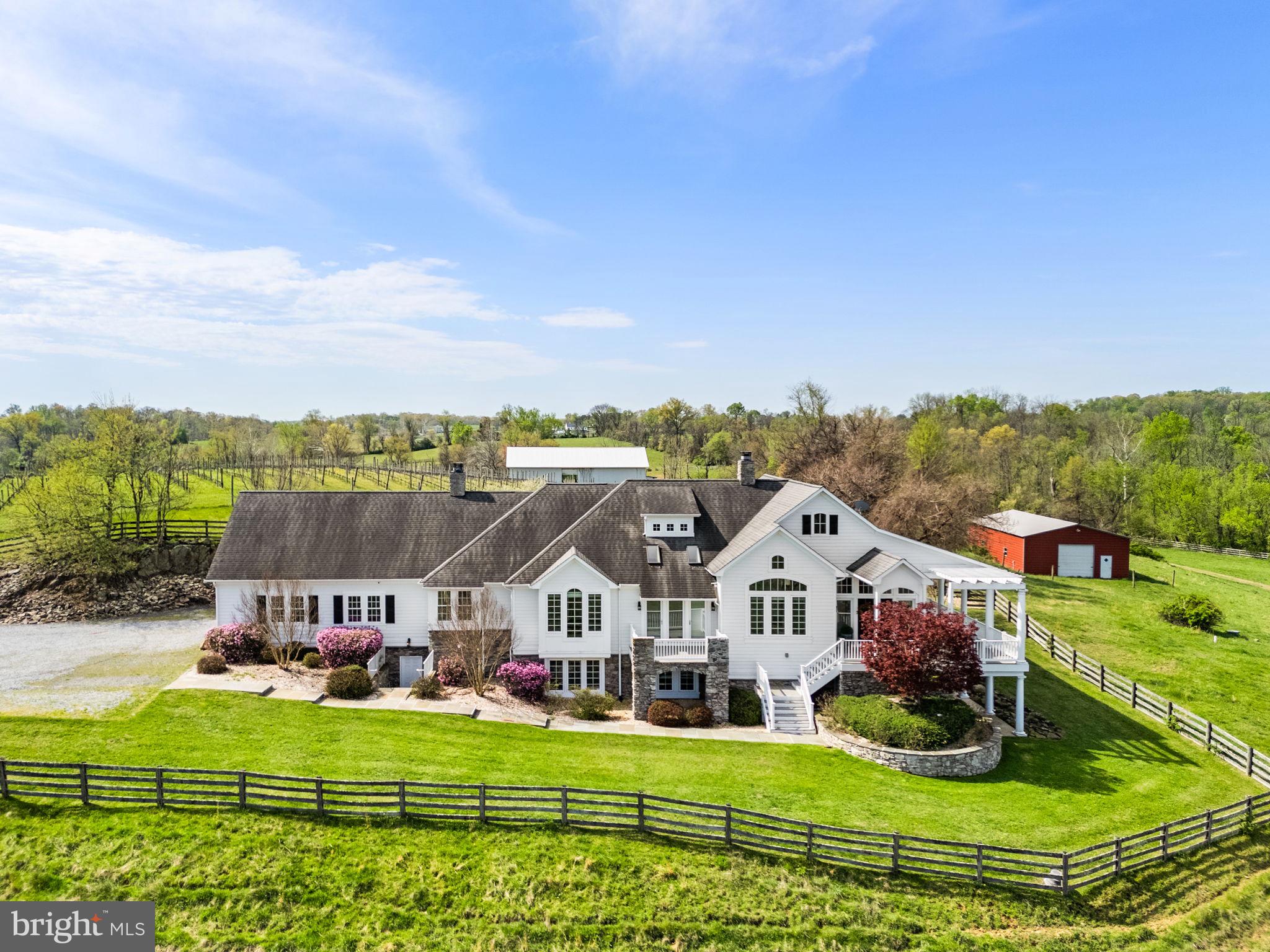 Nestled on over 14 private acres across 2 parcels, this exceptional custom Chadsworth estate offers refined country living just minutes from Round Hill and western Loudoun amenities. This property blends timeless craftsmanship, expansive living spaces, and breathtaking natural surroundings in a premier rural setting with no HOA.

A stately stone and HardiPlank exterior welcomes you to a thoughtfully designed residence featuring nearly 5,700 finished square feet across two levels, with additional unfinished space reflected in tax records. The main level offers true one-level living, anchored by a luxurious primary suite with hardwood floors, tray ceiling, spa-inspired bath with jetted tub, walk-in shower, his and her reading lights and generous walk-in closet (one of eleven total closets within the property). Additional main-level spaces include a formal foyer, sitting room, private office with two sets of French doors, den with built-ins, formal dining room with skylights and balcony access, and a warm living room with double-sided electric fireplace.

The country-style kitchen is both functional and inviting, featuring granite countertops, center island, double wall ovens, ENERGY STAR stainless appliances, skylights, and abundant cabinetry. The adjoining breakfast room includes a second electric fireplace and views of the surrounding landscape. A large mudroom and main-level laundry add everyday convenience.

The fully finished walkout lower level offers remarkable flexibility with four additional bedrooms, multiple Jack-and-Jill baths, a recreation room, bonus room, and den—ideal for guests, multi-generational living, or home-based workspaces. Each bedroom offers generous proportions, walk-in closets, and access to full baths.

Architectural details throughout include vaulted, tray, and two-story ceilings, hardwood flooring, chair rail and wainscoting, recessed lighting, skylights, and expansive windows that frame pastoral and creek views. The home is equipped with zoned HVAC, propane-owned heating system, humidifier, dehumidifier, air filtration system, and energy-efficient windows and appliances.

Outdoors, the property offers endless possibilities—gardening, recreation, or simply enjoying the serenity of creekside living. The attached side-entry two-car garage complements the home’s thoughtful layout, while the rural AR-1 zoning provides flexibility and multiple of potential use options.  The 30'x50' metal barn/workshop with electric coupled with the two stall run-in at the back of the property offer significant possibilities for future use. 

Conveniently located near Route 7, historic Round Hill, wineries, and outdoor recreation, and served by Round Hill Elementary, Harmony Middle, and Woodgrove High School, this rare offering combines acreage, water frontage, and luxury living in one of Loudoun County’s most scenic settings.

Note: aerial photography property lines on photos are an approximate estimation.