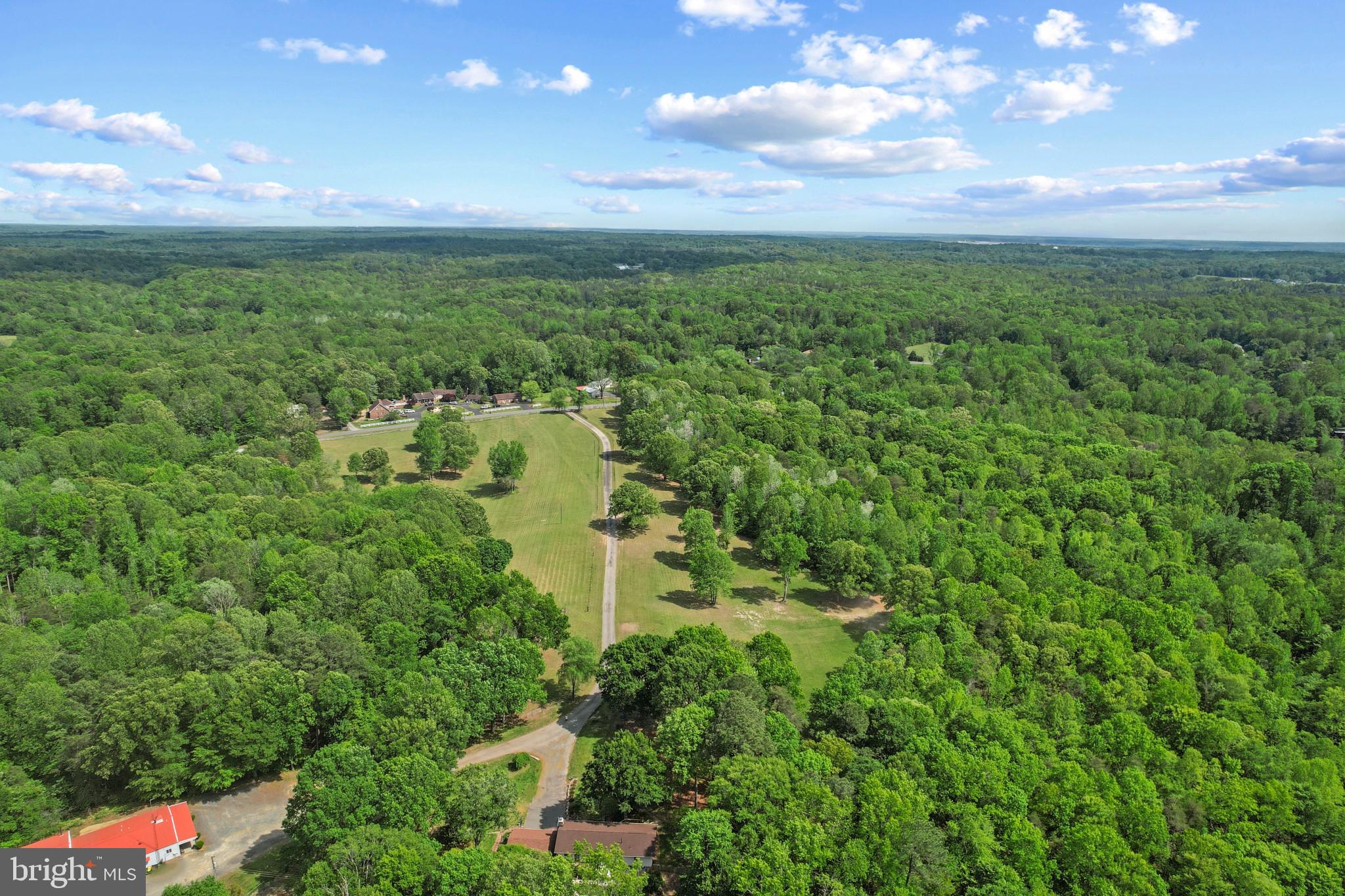 A rare private retreat with exceptional flexibility, this 55.67-acre Fredericksburg offering blends refined comfort, outdoor recreation, work-near-home capability, and room to breathe across three parcels. Thoughtfully upgraded in 2000 and enhanced with key recent improvements, the property feels both established and current, with a setting that invites privacy, possibility, and a lifestyle that is hard to find this close to modern conveniences. With Seller financing options now available for consideration with acceptable terms, this property may offer a creative home ownership opportunity rarely paired with this much land, infrastructure, and lifestyle appeal. 
At the heart of the property is a welcoming 4-bedroom, 2-bath bungalow designed for easy living and memorable gatherings. The oversized primary bedroom offers a true sense of retreat with a walk-in closet and a spa-inspired bath finished with marble tile, double vanity, walk-in shower, and jetted soaking tub. The kitchen brings substance and style together with a large center island, granite countertops, stainless steel appliances, and a Viking range hood in 2023. Open sightlines to the dining and living areas create a natural flow for everyday comfort, entertaining, and relaxed country-luxury living.
Step outside and the property becomes its own private resort. A heated saltwater pool with new vinyl liner in 2023, expansive decking, and hot tub create the perfect place to unwind or host. The pool house adds impressive function with a bar area, sink, refrigerator, ice maker, small kitchen, half bath, and outdoor shower. Nearby, the gazebo with hanging egg chairs and an overhead fan offers a shaded place to slow down and enjoy the surroundings.
For the entrepreneur, business owner, contractor, collector, hobbyist, or auto enthusiast, the high-bay shop and surrounding yard space are signature features. The shop and adjacent large parking, maintenance, and open storage areas have supported a successful tree service operation, including space for commercial vehicle maintenance, equipment staging, sawmill activity, and wood recycling. The high-bay shop offers room for up to seven large vehicles, a 10,000 lb lift, tool cages, commercial auto vacuum, restroom, wood stove, separate office area with half bath, and a 900 lb ice maker. Under the same roof is a cozy 2-bedroom apartment with walk-in closets, eat-in kitchen, living room, washer, and dryer, creating valuable flexibility for guests, extended living, studio use, office support, or other approved needs. 
The land is equally compelling. Enjoy your own 3-hole golf course, a private pond, creek frontage, partially wooded acreage, and abundant space for recreation, wildlife watching, and peaceful daily living. An additional non-contiguous parcel may also be available, offering community water access rights to Potomac Creek and the Potomac River, including access to a boat ramp and day pier, a standout opportunity for buyers who love the water.
Important recent improvements include a new architectural shingle roof in 2025, new well pump in 2025, new heat pump in 2023, new vinyl pool liner in 2023, and durable Hardie Board siding. Utilities include a private 8-inch drilled well over 300 feet deep with filtration and conditioning system, a 4-bedroom septic system per seller, 200 amp electric service at both the house and shop, and Verizon FiOS high-speed broadband, a notable advantage in a property of this size and setting. 
This is more than acreage. It is a private compound, a personal retreat, a recreation property, and a highly functional live-work lifestyle opportunity in one remarkable package. Whether your vision includes quiet mornings by the pond, poolside evenings, space for business equipment, room for prized vehicles, flexible guest accommodations, or simply a more private way to live, this Fredericksburg property deserves a closer look.