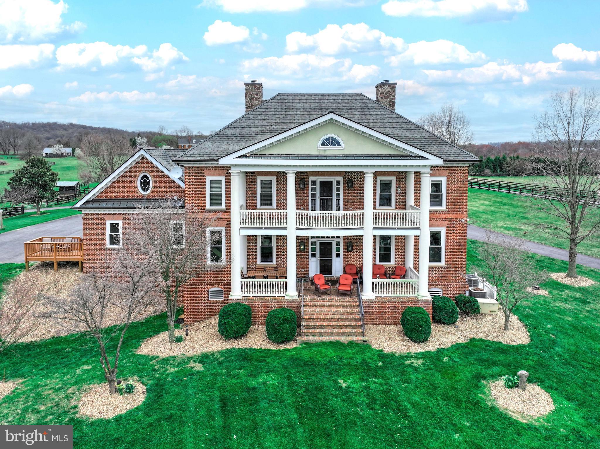 Welcome to your stunning custom Georgian style colonial home, nestled on nearly 15 acres of picturesque landscape with breathtaking views of the Blue Ridge Mountains. Inspired by the elegance of the governor's mansion, every aspect of this home has been meticulously crafted, leaving no detail untouched. 
 
From the moment you arrive, you'll be captivated by the charm of this residence. Adorned with four sides of Flemish bond brick, the exterior exudes timeless sophistication. Step onto the two-level main and upper-level covered verandas, offering sweeping vistas that stretch for miles. 

Inside, the Heart of Pine floors, reclaimed from an 1800’s barn in Massachusetts, infuse warmth and character throughout. Walnut doors, embellished with Baldwin Brass locks, and custom moldings add to the home's refined ambiance. 

Indulge in the comfort of four exquisitely appointed gas fireplaces, each adorned with period-style mantles, creating a cozy atmosphere in the main rooms of the main level. Original period-style lighting further enhances the home's charm. 

The gourmet kitchen features granite countertops, walnut cabinetry, and top-of-the-line appliances, including a SubZero refrigerator, Thermador gas range, and Asko dishwasher. A large walk-in pantry and butler's pantry ensure effortless entertaining. 

The fully finished walk-out basement, completed in 2021, offers additional living space, including a generous-sized family room, full bathroom, and two versatile rooms ideal for office space, a crafting room, or a home gym. 

For equestrian enthusiasts, this property is a dream come true. The land is meticulously set up for rotational horse grazing, with access to trails.  A three-stall barn, complete with a heated tack room, wash stalls, and vet station, provides all the amenities needed for horse care. Above the barn, a beautifully renovated space awaits, perfect for hosting meetings or converting into a living space or in-law apartment. 

Discover hidden gems throughout the property, such as the secret door concealing an additional room in the barn-style apartment. Spend leisurely afternoons fishing in the fully stocked pond or gliding across its surface in a paddle boat. As the day draws to a close, unwind on the veranda with your favorite beverage, soaking in the magnificent sunset. 

Welcome home to a lifestyle of luxury, tranquility, and unparalleled beauty.  *RECENT APPRAISAL OVER LIST PRICE*