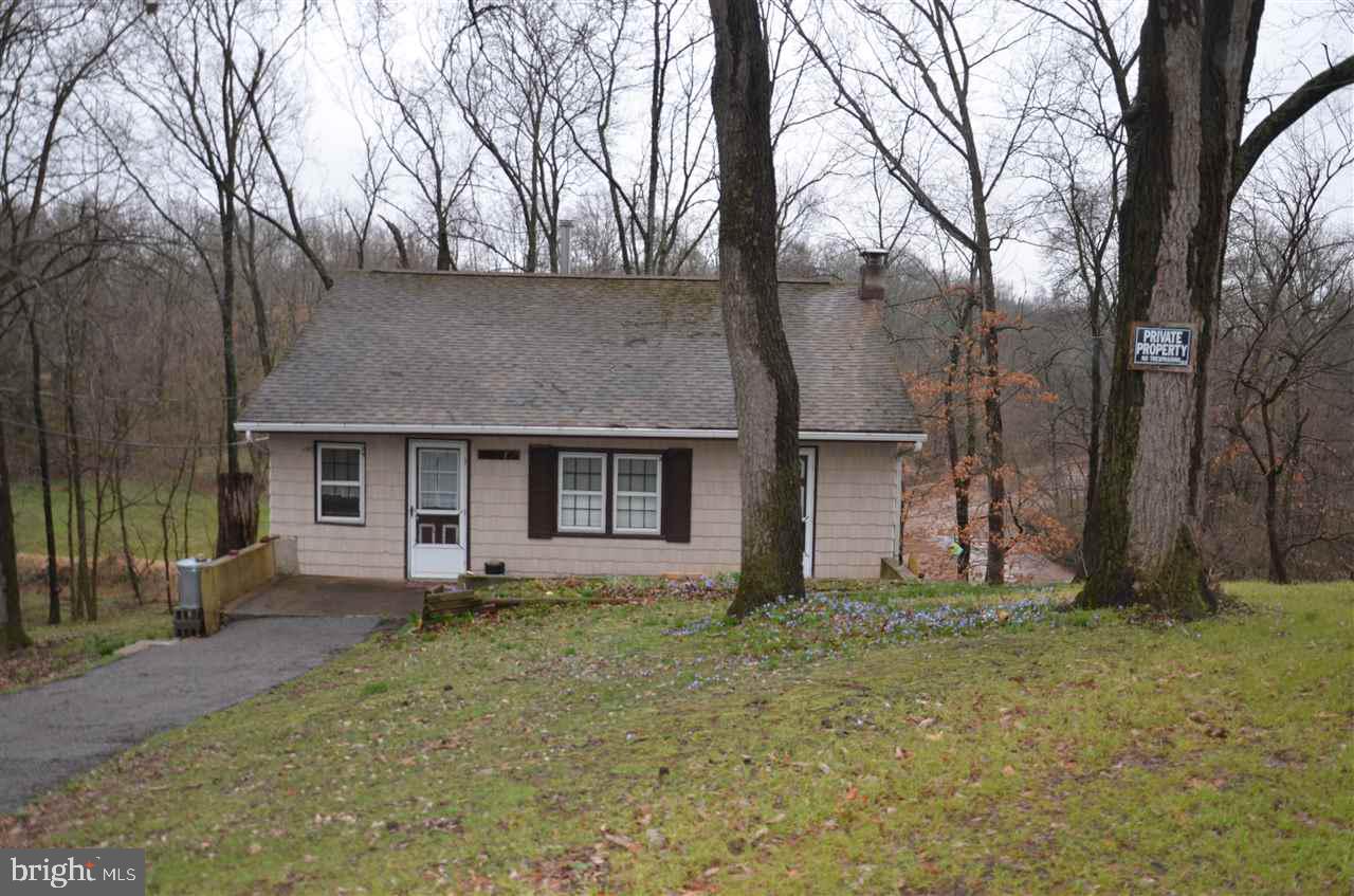 Rancher on the creek.  Sit on your deck, high above the creek & watch the animals play & the peaceful creek flow.  3BRS, LR w/ wood stove (one BR could be Sunroom or DR).  FR in BSMT w/ bar.  2-car GAR & large shed.  Public water & septic.  Tucked in the woods on 1 acre of land.  Cash only.  Seller will not make repairs.  Needs septic; could hook to sewer.
