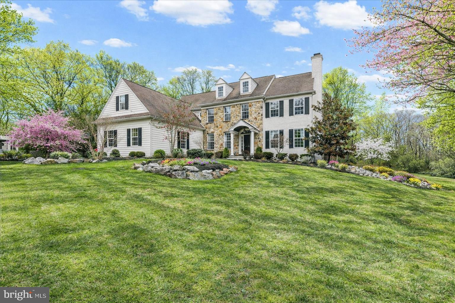 Experience your private retreat in Radnor Hunt—a timeless 5-bedroom, 3 full/3 half-bath stone Colonial offering over 6,593 square feet of impeccably designed living space on two beautifully landscaped acres with a tranquil pond and fountain. Exceptional flagstone patios, lush specimen plantings, and an in-ground sprinkler system enhance the picturesque setting, while the outdoor fireplace and built-in grill create an entertainer’s dream backdrop for unforgettable gatherings. A grand two-story foyer with a sweeping staircase introduces rich hardwood floors, refined architectural details, and sunlit interiors throughout. The formal living room features custom millwork, built-ins, and a marble-surround gas fireplace, while the elegant dining room—appointed with wainscoting, chair rail, and detailed moldings—sets the stage for memorable celebrations. At the heart of the home, the gourmet kitchen is thoughtfully designed with an oversized island, Sub-Zero refrigerator, and generous pantry, flowing seamlessly into the inviting family room with its striking stone hearth and gas fireplace. The adjacent breakfast area captures serene water views and opens to the rear patio, blending indoor and outdoor living with ease. A private study with French doors and a well-placed powder room complete the main level. An additional staircase leads to the upper level, where spacious bedrooms with walk-in closets provide comfort and function. The sumptuous primary suite offers a sitting area, dual walk-in closets, and a luxurious bath featuring double vanities, a Jacuzzi tub, and a separate shower—creating a true private retreat. The finished lower level expands the living space with a large game area, 6+ seat home theater, powder room, abundant storage, and convenient Bilco door access, offering flexibility for recreation, fitness, or media. An attached three-car garage and asphalt driveway add everyday convenience. Ideally located just minutes from Malvern Borough and the vibrant “new” King Street, enjoy boutique shopping, acclaimed dining, and rail service via SEPTA to Philadelphia and beyond. With close proximity to the Pennsylvania Turnpike, Great Valley Corporate Center, Wegmans, Target, Routes 30, 202, and 100, and Philadelphia International Airport, this distinguished property offers the perfect blend of luxury, privacy, and accessibility—an exceptional opportunity in one of the Main Line’s most coveted settings.