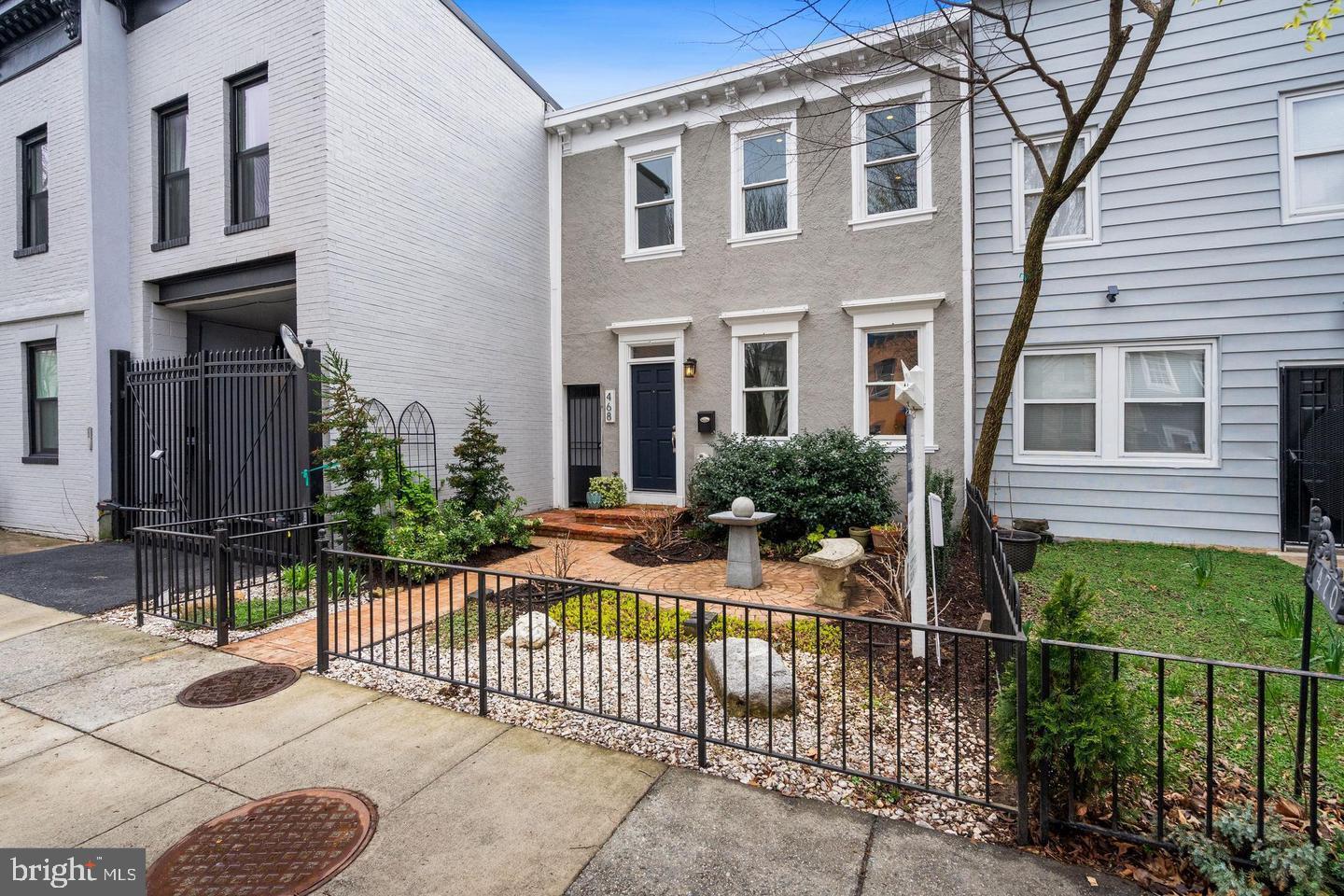 Welcome to this classic federal style row home in one of the city’s most vibrant neighborhoods. This charming home with a gated entry has a beautiful, landscaped front yard. The foyer opens onto a large and open main level. Living room with a custom built-in bookshelf. The open concept kitchen with an island, stainless steel appliances, ample of cabinets, and timeless quartz countertops. Utility closet with a new washer and dryer plus a powder room.  Dining area with a back door that leads into the paved and fenced back patio, with a kitchen-side bar and landscaped seating area featuring a mature crape myrtle tree.  The upper level provides two generous bedrooms and two baths. The secondary bedroom with northern exposure has ample space for a bedroom and storage configuration. Its adjacent bathroom features travertine tile and granite counters, as well as a surprisingly large linen closet. The primary suite is certainly large enough to be divided into a bedroom and office space. Its en-suite bath includes a double vanity configuration, and natural stone tile and countertops. All this plus a parking pad makes this home just perfect.