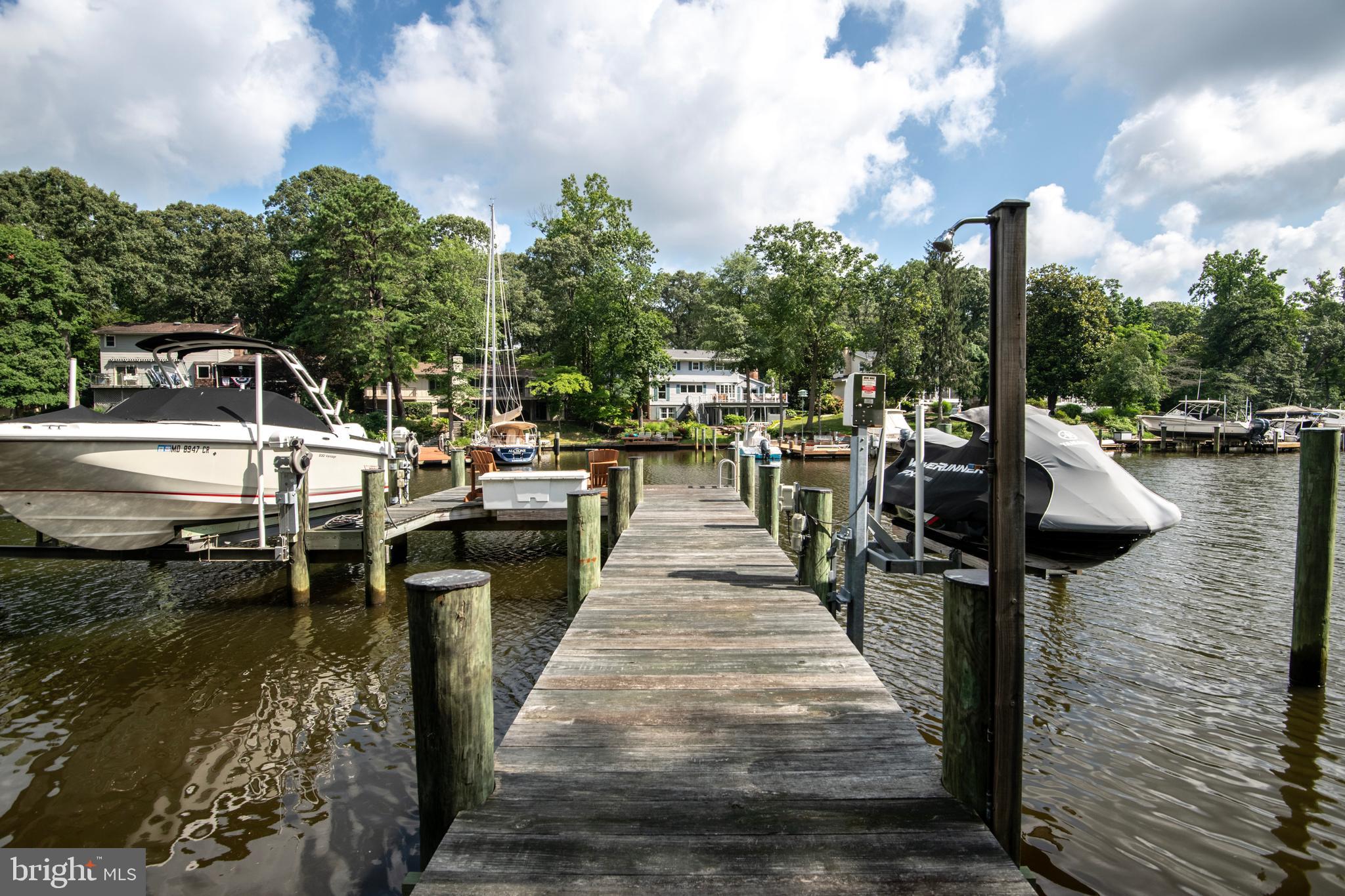This isn’t just a home — it’s a lifestyle. Set on over 2 private wooded acres with more than 500 feet of water frontage, 34 Chartham Lane offers the rare opportunity to vacation at home every single day. Whether you're boating, paddleboarding, entertaining on the deck, or simply enjoying the view — life here feels like an amazing getaway. The private pier features a 10,000 lb boat lift, a separate jet ski lift, and an area to launch kayaks, making it easy to spend your days out on the water. After a day on the creek, come back and relax in the hot tub overlooking your peaceful, tree-lined property, or gather with friends on one of the three custom decks for a sunset drink. Inside, you'll find 5 bedrooms and 5 full bathrooms, with flexible living spaces designed to grow with your needs. The main level study and lower-level media room could easily serve as a 6th or 7th bedroom. The updated kitchen with its large island opens to a sunny living space anchored by a beautiful stone fireplace — the perfect backdrop for everyday living and effortless entertaining. The lower level offers a huge media room, ideal for movie nights, game days, or a quiet space to unwind. There’s also ample storage, giving you room to stay organized and clutter-free. Every detail was thoughtfully designed — from the HardiePlank siding and stone water table to the custom portico and irrigation system. Natural light pours through the home, highlighting water views from nearly every room and bringing the outdoors in. Located within the highly rated Severna Park school district and just minutes from shopping, dining, and commuter routes — this is a rare waterfront home that offers it all: privacy, beauty, and the convenience of everyday living. Welcome Home!