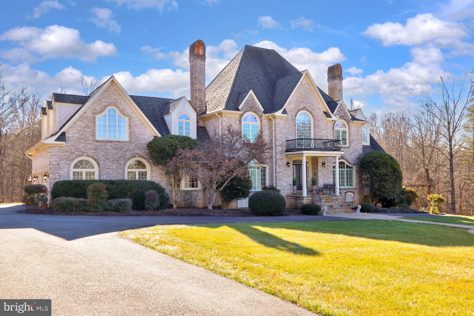 Welcome to 6601 Stonecrest Lane in Fairfax Station, Virginia! Nestled in a relatively small enclave of luxury homes, this 4 bedroom, 4.5 bath French country chateau delivers finely crafted living space and is infused with upscale millwork and designer finishes. The appeal begins outside with a stately 3-sided brick exterior with portico entrance, hardscaped water feature, 3-car side-loading garage, expansive deck, sparkling in-ground pool and hot tub, and a lush and vibrant 5-acre lot. Inside, marble, hardwood flooring, custom moldings, plantation shutters, a soft designer color palette, recessed and designer lighting, and an abundance of windows and skylights are only some of the reasons this home is so special. The perfect blend of personal and family-oriented zones creates instant appeal.
 
A gently winding staircase greets you in the grand two-story foyer, as hand laid marble flooring ushers you into the flowing floor plan. To the right, the light-filled living room is highlighted by a wood-burning fireplace and an adjoining sunroom that delivers spectacular panoramic views. Opposite the foyer, the banquet-sized dining room offers plenty of space for all occasions, as wainscoting and a candelabra-style chandelier add a distinctly refined flair. The gourmet kitchen stirs the senses with gleaming granite countertops and corresponding backsplash, handcrafted cabinetry, and stainless-steel appliances including double wall ovens and a commercial grade refrigerator. Enjoy morning coffee in the breakfast area, sitting fireside in the two-story great room, or step outside to the multi-area deck with descending stairs to an expansive patio, sparkling in-ground pool with hot tub, gardener's shed, and idyllic 5-acre lot beyond—seamlessly blending indoor and outdoor living, dining, or simple relaxation! Back inside, a library with fireplace built-in shelving, and a powder room with a furniture-style vanity complement the main level.
 
Upstairs, the primary bedroom suite beckons with room for a sitting area, a large walk-in closet along with additional closet space, and a private bath boasting Architectual cathedral ceilings, dual vanities, a sumptuous soaking tub, glass-enclosed ultra shower, and spa-toned tile flooring and surround—the finest in personal pampering! Down the hall, two additional bright and spacious bedrooms, each with plush carpet and generous closet space, share access to the beautifully appointed hall bath with dual-sink vanity, as a bedroom level laundry center eases the daily task. This uppermost level harbors a junior suite with a private bath and an additional sitting room that provides the versatile space to suit the needs of your lifestyle. There is a private entry and back staircase making for an ideal au pair suite or homes office. Fine craftsmanship continues in the walkout lower-level recreation room that delivers space for games, media, and exercise; as two versatile bonus rooms, an additional full bath with steam shower, and ample storage solutions complete the comfort and luxury of this wonderful home.
 
All this can be found in a peaceful setting that feels miles away from the hustle and bustle yet is so close to Route 123, the Fairfax County Parkway, Burke VRE, and Metro access. The nearby charming Town of Clifton offers historic landmarks, cafés, and boutique shopping where you can experience a leisurely afternoon at popular Paradise Springs Winery enjoying tastings, tours, and events alongside the Bull Run River. For a suburban retreat that offers sophistication and comfort, you’ve found it. Welcome home!