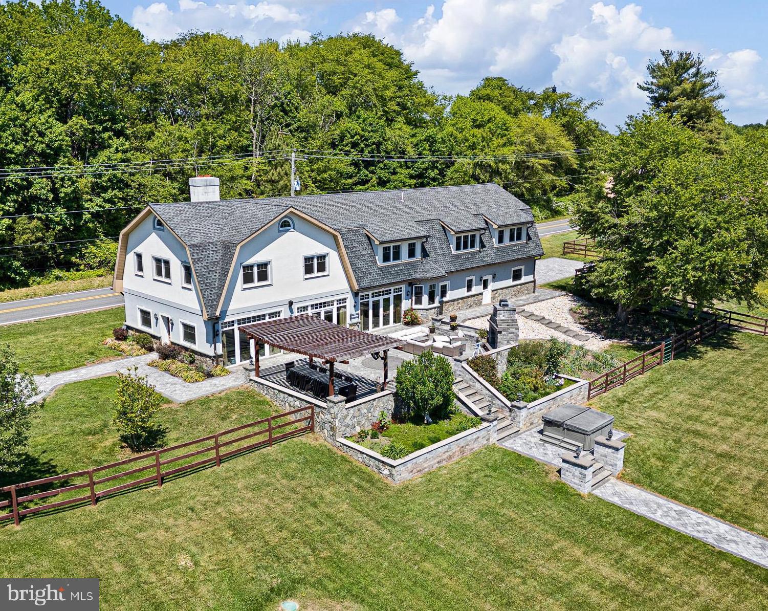 What began as a 1905 barn has been transformed into one of Townsend’s most extraordinary private residences. Rebuilt from the ground up in 2011 with intention, craftsmanship, and uncompromising attention to detail, this custom luxury estate blends the soul of its historic origins with the elevated design and functionality of a modern retreat. Set on 4.64 picturesque acres surrounded by open land, marsh views, mature trees, and water in the distance, the property offers a level of privacy and serenity that feels worlds away while still remaining accessible. The exterior maintains the striking character of the original barn with its classic gabled architecture, stucco finish, and stone façade, while a long paved driveway, detached two-car garage, and additional barn structure create a true estate-like arrival. Inside, the scale and natural light immediately leave an impression. The main level was designed for both everyday living and unforgettable entertaining, with soaring ceilings, custom tray details, and an entire wall of windows and doors framing the surrounding landscape like artwork. Heated travertine flooring flows throughout the first floor, while a dramatic stone wood-burning fireplace anchors the expansive living and dining spaces. At the center of the home is a truly exceptional chef’s kitchen. Thoughtfully designed and beautifully executed, it features extensive custom cabinetry, black granite countertops, a massive contrasting island with seating, dual farmhouse sinks, two dishwashers, stainless steel appliances, induction cooktop with exterior vented hood, beverage cooler, walk-in butler’s pantry, and a dedicated eat-in area surrounded by views of the property. Every detail was considered, from the soft-close cabinetry to the custom lighting and built-in workspace. The home continues to impress upstairs, where over 10-foot ceilings and tigerwood hardwood flooring carry throughout the second level. The primary suite feels like a private sanctuary, complete with cathedral ceilings, exposed wood beams, dual walk-in closets, and a spa-inspired ensuite featuring heated marble floors, towel warmer, jacuzzi tub, double vanity, and an oversized rain shower. Two additional guest bedrooms each offer walk-in closets, while a large bonus room provides flexibility for a fourth bedroom, office, studio, or additional lounge space. The secondary full bath mirrors the same elevated finishes with heated travertine floors, double vanities, soaking tub, and a spacious walk-in shower. Beyond the home itself, the lifestyle this property offers is what truly sets it apart. Step outside onto an expansive paver patio designed for gathering and entertaining, complete with a wood-burning outdoor fireplace, multiple seating areas, and illuminated stone walkways leading you through the property. The private pond becomes a centerpiece of the landscape, surrounded by walking paths, additional seating areas, and a floating sun deck that invites quiet mornings and sunset evenings alike. The grounds are fully fenced and thoughtfully arranged with two open pastures, each with dedicated shelters for animals, making the property ideal for hobby farming, equestrian use, or simply enjoying the openness of the land. Two acres are maintained by an automated robotic lawn system included in the sale. An additional detached barn structure offers extraordinary flexibility and potential. Currently configured around the owner’s passion for koi fish breeding, the space includes substantial infrastructure and storage, but could easily be reimagined into stables, workshop space, studio space, car storage, or countless other possibilities depending on the next owner’s vision. This is not simply a home. It is a property built around lifestyle, craftsmanship, privacy, and passion. A truly rare offering where luxury living meets rural tranquility in a way that is almost impossible to replicate.