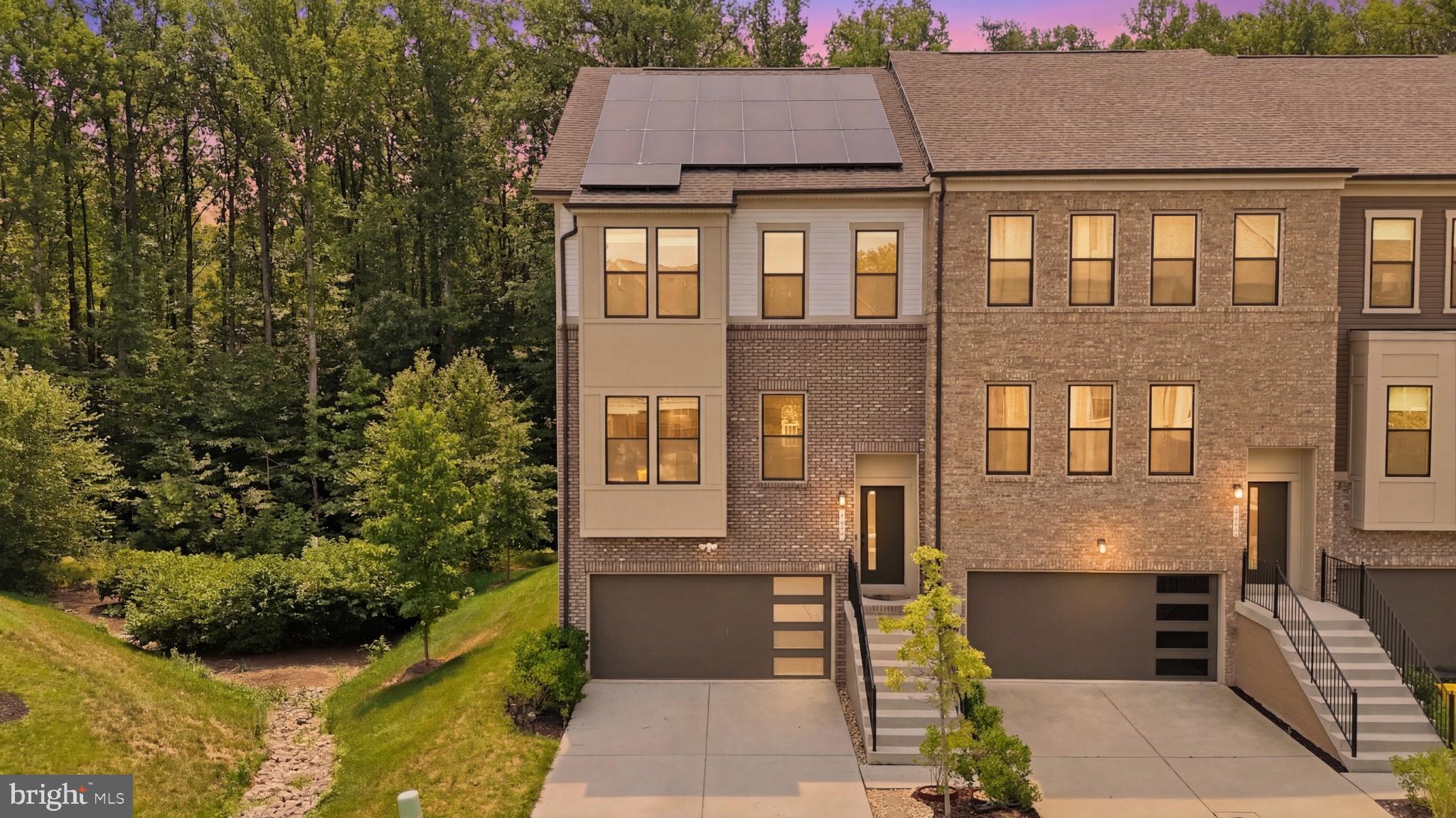 Rarely does a home combine luxury, privacy, and long-term financial value quite like this. Welcome to one of Watershed’s most coveted residences—a recently built, four-level end-of-group townhome loaded with premium builder upgrades and perfectly positioned on a premier homesite backing to protected woods for exceptional privacy and picturesque views. Topping it all off is an incredible rooftop terrace where mornings begin with peaceful tree-lined vistas and evenings end beneath the stars. Even more impressive, the home conveys with 23 FULLY OWNED solar panels—no lease, no loan, no transfer payments—offering immediate savings from day one. The 9.2 kW system features 23 premium 400W Q CELLS panels with Enphase microinverters, has exported over 5,829 kWh back to the grid, averages approximately just $32 per month in electric costs, and has generated thousands in energy savings while providing valuable SREC income opportunities for the homeowner. Enter into sun-drenched interiors enhanced by the abundance of windows exclusive to an end residence, where a fresh neutral palette, brand-new paint, luxury vinyl plank flooring, and brand-new carpet create a timeless aesthetic. The expansive main living level is designed for effortless entertaining and showcases a chef-inspired kitchen featuring frost white quartz countertops, 42-inch espresso cabinetry, stainless steel appliances, recessed lighting, a spacious walk-in pantry, and seamless flow into the dining and family rooms adorned with upgraded designer lighting and elegant window treatments throughout. Extend your living space outdoors onto the private Trex deck overlooking mature woods, creating a peaceful retreat rarely found in townhome living. The luxurious owner’s suite offers generous proportions, a walk-in closet, ceiling fan, and spa-inspired bath with dual granite vanities, oversized walk-in shower, private water closet, and 42-inch cabinetry. Two additional bedrooms, an upper-level laundry room, and a beautifully appointed hall bath complete the bedroom level. Ascend to the spectacular fourth-floor loft—a flexible space ideal for a media room, executive office, fitness studio, or guest retreat—with direct access to the rooftop terrace overlooking the tree canopy. The entry level features a private bedroom and full bath, mudroom, walkout access to the backyard, and entry to the oversized two-car garage. Completing this exceptional offering are a two-car garage, two-car driveway, abundant guest parking, attractive brick water table, and access to Watershed’s resort-style amenities including a clubhouse, outdoor pool, fitness center, dog park, playgrounds, and miles of scenic walking and biking trails. Perfectly positioned just minutes to I-95, Routes 32, 100 and 295, NSA, Fort Meade, BWI Airport, MARC Rail, Target, Walmart, Panera, shopping, dining, and everyday conveniences, this extraordinary residence delivers the rare combination of luxury, efficiency, privacy, and lifestyle that today’s discerning buyers have been waiting for.