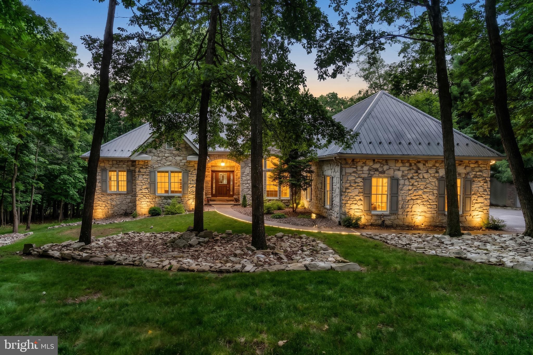 Perched at the top of White Rock Acres at the end of a quiet cul-de-sac, this meticulously maintained stone ranch style home offers versatile living space, superior updates, and picturesque wooded views. You will find all of  the “extras” that you would expect throughout the home such as pristine hardwood floors, epoxy coated floors in the basement workshop and garage, humidifier, whole home air purification system, Anderson windows and doors, built-ins, composite decking and so much more!  The main level features a formal dining room, gorgeous family room with propane fireplace, and updated kitchen with breakfast room, custom cabinetry, pantry and granite countertops. The primary suite offers a sitting area with access to the deck, spacious primary bath, and two walk-in closets. 2 additional bedrooms and main level laundry room round out the main level.  The finished lower level expands the home’s functionality with an additional bedroom with walk-in closet and full bath, and second kitchen. (The perfect in-law suite!)  Also in the lower level you will find a spacious office featuring a 2-sided propane fireplace, and a dedicated theater room with Bose sound system—ideal for work, recreation, and entertaining. Outdoor amenities include a new composite deck (2025) overlooking the private wooded backyard and a detached 14’ x 32’ garage (2018) providing ample storage and workspace. Additional recent improvements include a new metal roof (2024), Energy Smart home insulation (2024), LeafFilter gutter protection (2020), and new HVAC system (2020), offering peace of mind and energy efficiency. This thoughtfully updated property combines flexible living areas, modern upgrades, and a picturesque setting in a desirable location.