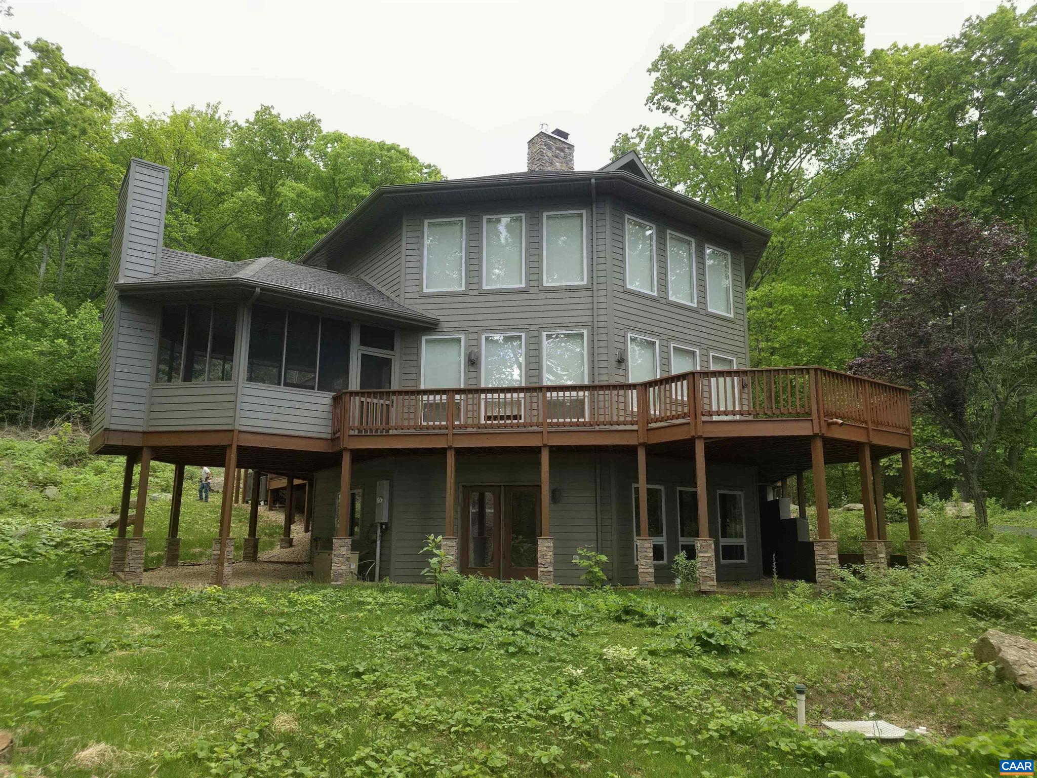 Perched near the top of Stoney Creek on 2.74 private acres, this renovated 3,400+ sq ft mountain retreat offers panoramic Rockfish Valley views, exceptional privacy, & a rare high-elevation setting. The home centers around a dramatic two-story stone fireplace connecting the great room, dining area, kitchen, & loft-style primary suite above. The updated kitchen features white shaker cabinetry, quartz counters, stainless appliances, a large island, & updated lighting. Outdoor living is a major highlight, w/ wraparound decking, a screened porch w/ fireplace, & a rooftop patio above the garage w/ hot tub hookups. Additional flex spaces, a dedicated office/library, & a large lower-level recreation area provide room for guests, work, hobbies, or extended stays. Natural boulders, mature woods, & the elevated setting create a true mountain-lodge feel just minutes from Wintergreen Resort, golf, hiking, wineries, breweries, & Rockfish Valley amenities. Compelling value for one of Stoney Creek?s most private view homes. The HOA allows short-term rentals, & w/ its privacy, views, resort proximity, outdoor living spaces, & flexible layout, the property may appeal to buyers seeking a second home, mountain getaway, or potential income off-set.,Quartz Counter,White Cabinets,Wood Cabinets,Exterior Fireplace,Fireplace in Living Room