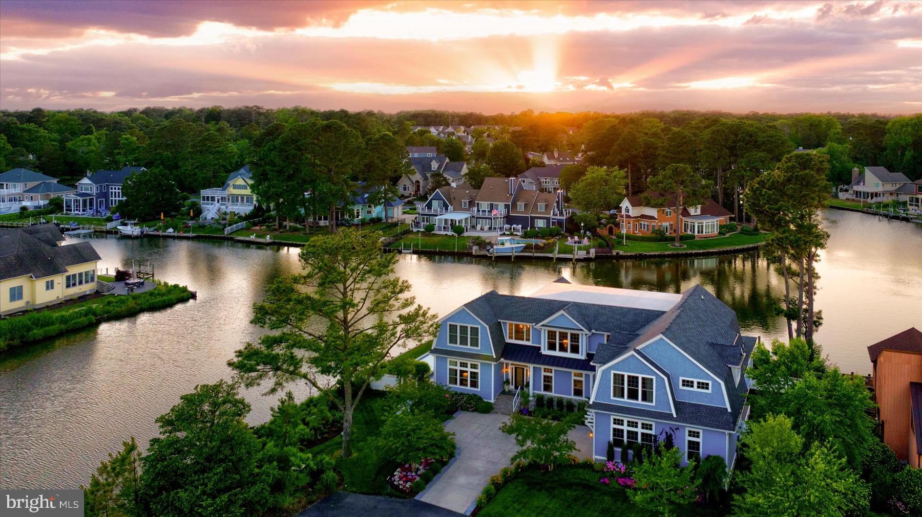 At the intersection of three canals in Rehoboth Beach Yacht & Country Club, Blue Gables occupies one of the most extraordinary waterfront parcels on the Delaware coast. This published, award-winning estate offers more than 275 feet of bulkheaded waterfront, a deep-water dock, and sweeping water views from every room. Featured in Coastal Living and selected as Best Overall Home in the 2024 Rehoboth Cottage Tour, the custom residence spans more than 6,000 square feet of refined coastal luxury, with 7 bedrooms, 7 full baths, and elevator access to both levels.

Designed for both grand-scale entertaining and effortless everyday living, the home is anchored by a dramatic great room with soaring 20-foot barrel-vault ceilings and expansive folding glass doors that open to a wraparound covered porch overlooking the water. Outside, a spectacular custom pool by Ashton Pools serves as the centerpiece of the resort-inspired grounds and earned international recognition as one of PebbleTec’s 2019 World’s Greatest Pools.  Complementing the estate's unparalleled waterfront setting, the deep-water dock provides direct boating access and completes the property's resort-like lifestyle. 

The chef’s kitchen is appointed with Sub-Zero refrigeration, an Italian ILVE range, striking stone surfaces, and an adjoining caterer’s kitchen with additional refrigeration, dishwasher, wall oven, ice maker, and generous support space for entertaining. Thoughtfully designed for multigenerational living, the residence includes a luxurious first-floor primary suite with water views, an expansive dressing room, and a fully accessible spa-inspired bath. A second main-level bedroom or private sitting room offers exceptional flexibility.

Upstairs, five generously sized en-suite bedrooms are joined by a library with custom built-ins, a dedicated office, and a fully independent au pair or in-law suite ideally suited for extended family, live-in assistance, or long-term guests. Just moments from the beach, boardwalk, golf courses, and downtown Rehoboth Beach, Blue Gables represents a rare opportunity to own an award-winning waterfront estate in one of coastal Delaware’s most coveted settings.