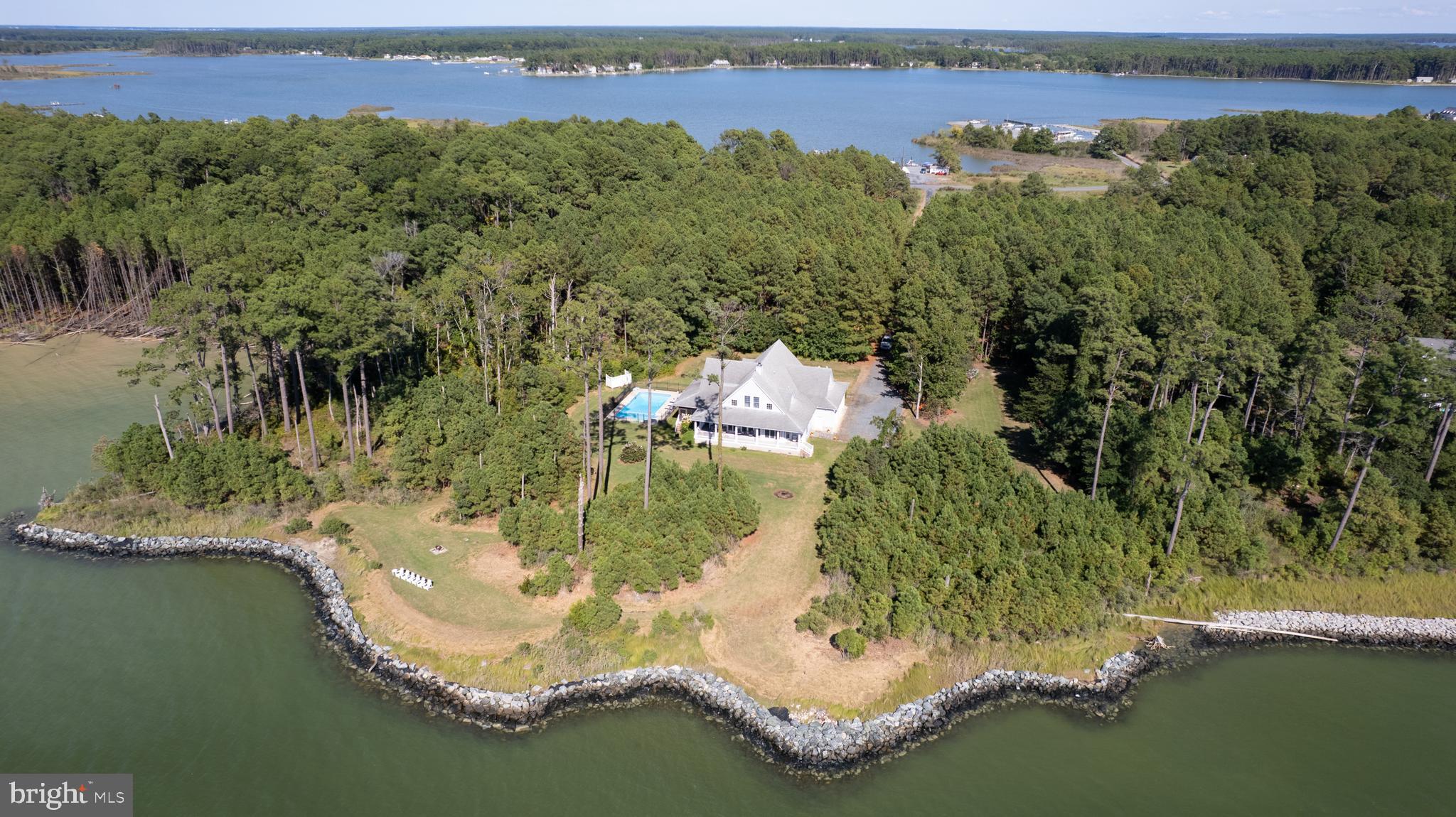 Set on 10 remarkably private acres in Dorchester County’s scenic Neck District, this custom-built waterfront retreat commands sweeping views of the Middle Chesapeake Bay and offers the rare combination of space, comfort, and true Eastern Shore serenity. With over 4,500 sq. ft., 6 bedrooms, 4.5 baths, rip-rapped shoreline, and exceptional indoor and outdoor living spaces, this is a property designed for gathering generations of family and friends.

A long private approach welcomes you to a setting where nature and waterfront living take center stage. Inside, hardwood floors, timeless architecture, and expansive Bay views create a warm yet elegant atmosphere. The waterfront family room features a striking stone fireplace with wood-burning insert and opens seamlessly to both the screened porch and covered deck, creating effortless indoor-outdoor living. The spacious kitchen was designed with entertaining in mind, offering a center island, breakfast bar, abundant cabinetry, stainless steel appliances, double wall ovens, pantry storage, and an oversized breakfast room ideal for casual mornings by the water. Formal living and dining rooms provide additional space for hosting holidays and special occasions.

The first-floor primary suite serves as a private waterfront sanctuary with direct access to the covered porch and peaceful Chesapeake Bay views. Upstairs, five spacious guest bedrooms and three full baths—including a private en-suite—offer flexibility for large families, guests, or vacation rental potential. Vaulted ceilings and dormer windows add architectural charm and natural light throughout the second level.

Outside, the lifestyle only gets better. Spend summer days around the inground pool, rinse off in the outdoor shower after boating or kayaking, enjoy crab feasts on the screened porch, or gather around the waterside fire pit as the sun sets across the Bay. The partially wooded acreage provides exceptional privacy while attracting an abundance of wildlife including bald eagles, deer, ducks, geese, and shorebirds—an everyday reminder of the natural beauty that surrounds you.

Located on Ragged Point with Eastern Shore favorites like Soft & Salty Seafood and Danny's Seafood, this property offers easy access to fresh seafood, marinas, boating, and some of the finest fishing and crabbing waters on the Chesapeake Bay.  The nearby Neck District Grill is a great spot for breakfast, lunch or weekend dinner.  

Whether you are searching for a full-time waterfront residence, luxury weekend escape, or investment opportunity with proven vacation rental appeal, this extraordinary property delivers the privacy, waterfront lifestyle, and authentic charm that buyers are seeking on Maryland’s Eastern Shore.