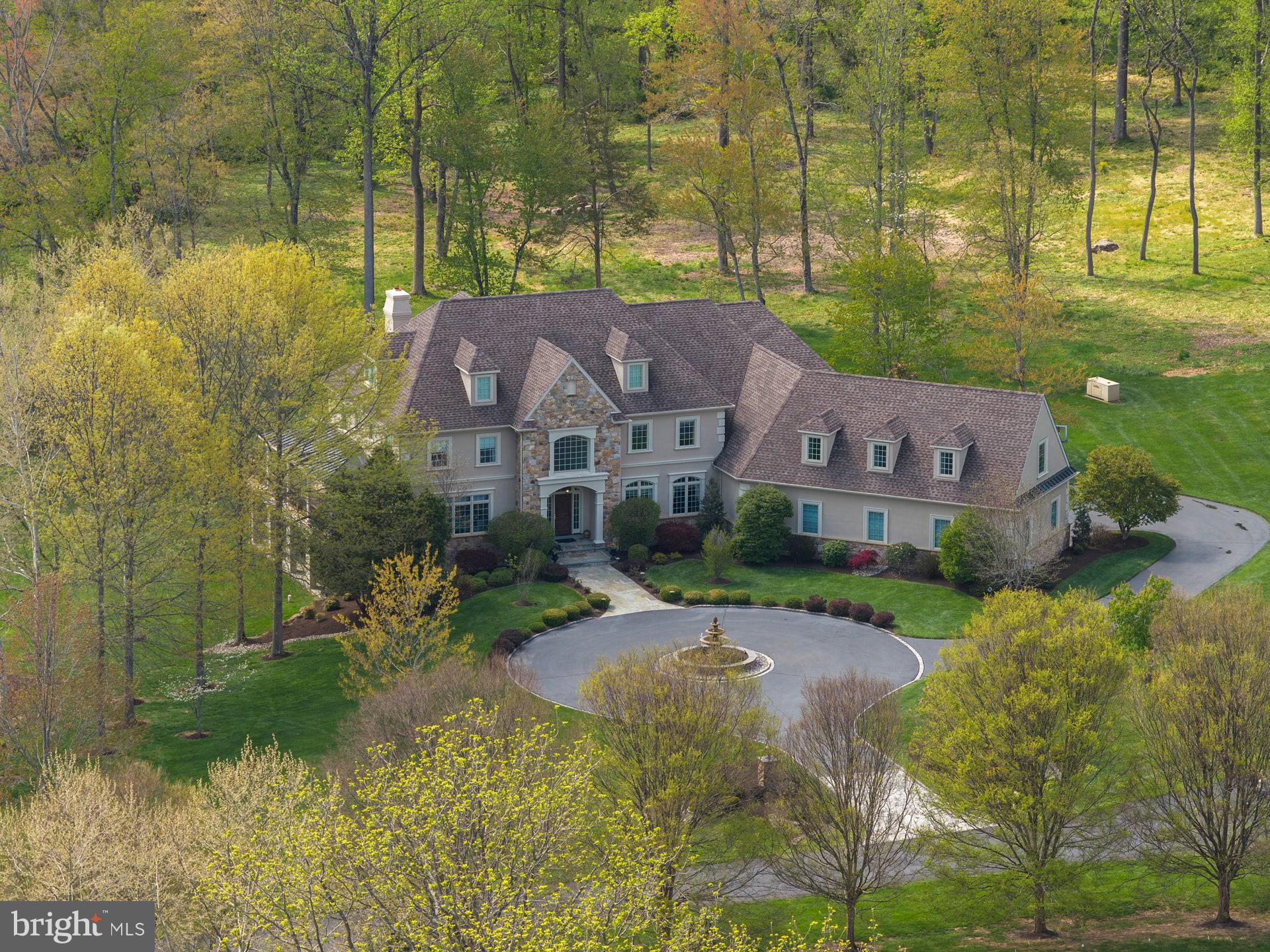 Experience exceptional luxury on 4+ acres in one of Solebury Township’s most coveted enclaves. Ideally positioned on a cul-de-sac, this custom-built Bucks County estate offers a rare combination of acreage, privacy, and architectural presence—introduced by a stately circular drive and fountain that set the tone for what lies beyond.

Step into the marble foyer with a gorgeous curved staircase and premium trim work.  Designed with both everyday living and elevated entertaining in mind, the chef’s kitchen features radiant heated floors, professional-grade stainless appliances, expansive granite surfaces, and an oversized center island with secondary dishwasher and refrigerated drawers. The dramatic 20+ foot high coffered family room is anchored by a stone wood-burning fireplace and framed by walls of windows overlooking a serene lawn and beautiful treed meadow beyond. Formal living room with gas fireplace, formal dining room, a butler’s pantry complete with wet bar, and a private office featuring custom built-ins and access to a wrap-around covered porch complete the main level.

Upstairs, the primary suite offers a true sense of retreat, with a spacious sitting area, dual walk-in closets, tray ceilings, and a separate flex space ideal for a custom walk-in closet, gym, or perhaps a large second floor laundry room. The spa-inspired bath features a steam shower, jetted soaking tub, dual vanities, and radiant heated floors. Three additional ensuite bedrooms and a full third-floor princess suite provide comfort and privacy for family and guests.

The finished lower level is thoughtfully designed for entertainment, featuring a pub-style bar, gaming area, a dedicated home theater with projection and surround sound, along with another bonus room, a full bath, and a large workshop. And its wall of windows and connection to the backyard do not disappoint.

Outdoors, the 4.25 acres offer endless potential, with ample space for a future pool and outdoor kitchen, complemented by patios and a wrap-around covered porch. Additional amenities include a generator, an alarm system, and a heated 4+ car garage with premium SwissTraxx flooring, many cabinets and shelves, and stairs leading directly to the basement.

Located within the award-winning New Hope–Solebury School District and just minutes from the vibrant rivertowns of New Hope and Lambertville—with convenient access to New York, New Jersey, and Philadelphia—this property represents a rare opportunity to own a private estate of this scale and caliber in the heart of Bucks County.