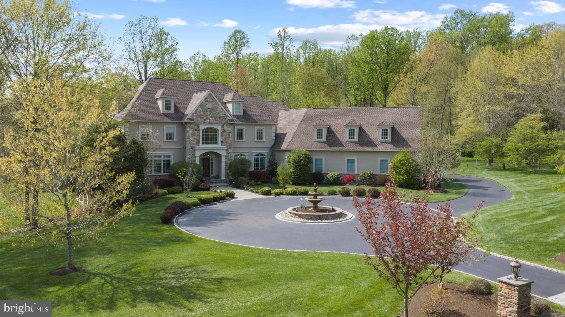 Experience exceptional luxury on 4+ acres in one of Solebury Township’s most coveted enclaves. Ideally positioned on a cul-de-sac, this custom-built Bucks County estate offers a rare combination of acreage, privacy, and architectural presence—introduced by a stately circular drive and fountain that set the tone for what lies beyond.

Step into the marble foyer with a gorgeous curved staircase and premium trim work.  Designed with both everyday living and elevated entertaining in mind, the chef’s kitchen features radiant heated floors, professional-grade stainless appliances, expansive granite surfaces, and an oversized center island with secondary dishwasher and refrigerated drawers. The dramatic 20+ foot high coffered family room is anchored by a stone wood-burning fireplace and framed by walls of windows overlooking a serene lawn and beautiful treed meadow beyond. Formal living room with gas fireplace, formal dining room, a butler’s pantry complete with wet bar, and a private office featuring custom built-ins and access to a wrap-around covered porch complete the main level.

Upstairs, the primary suite offers a true sense of retreat, with a spacious sitting area, dual walk-in closets, tray ceilings, and a separate flex space ideal for a custom walk-in closet, gym, or perhaps a large second floor laundry room. The spa-inspired bath features a steam shower, jetted soaking tub, dual vanities, and radiant heated floors. Three additional ensuite bedrooms and a full third-floor princess suite provide comfort and privacy for family and guests.

The finished lower level is thoughtfully designed for entertainment, featuring a pub-style bar, gaming area, a dedicated home theater with projection and surround sound, along with another bonus room, a full bath, and a large workshop. And its wall of windows and connection to the backyard do not disappoint.

Outdoors, the 4.25 acres offer endless potential, with ample space for a future pool and outdoor kitchen, complemented by patios and a wrap-around covered porch. Additional amenities include a generator, an alarm system, and a heated 4+ car garage with premium SwissTraxx flooring, many cabinets and shelves, and stairs leading directly to the basement.

Located within the award-winning New Hope–Solebury School District and just minutes from the vibrant rivertowns of New Hope and Lambertville—with convenient access to New York, New Jersey, and Philadelphia—this property represents a rare opportunity to own a private estate of this scale and caliber in the heart of Bucks County.